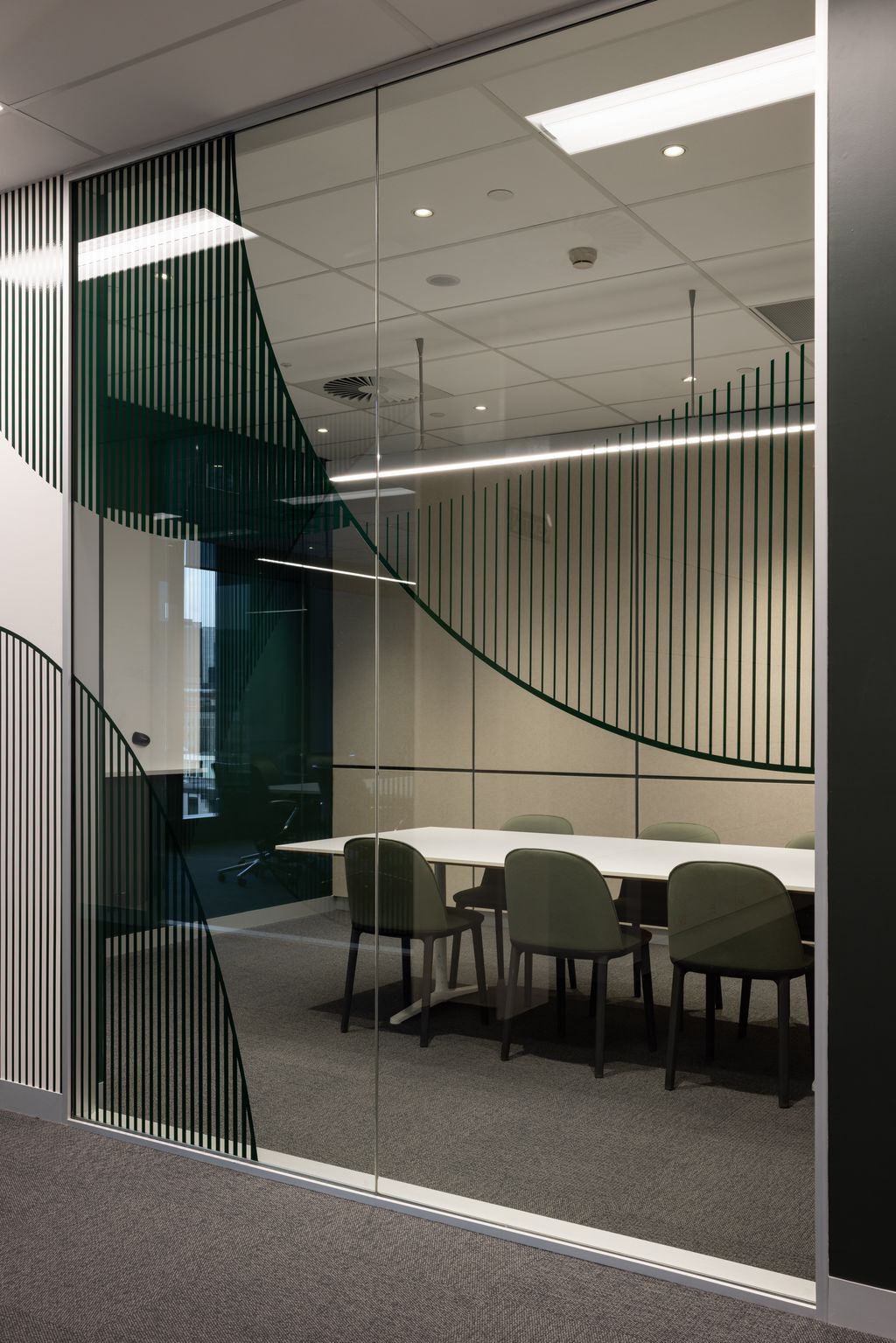 Modern office conference room with glass walls and a table with chairs.