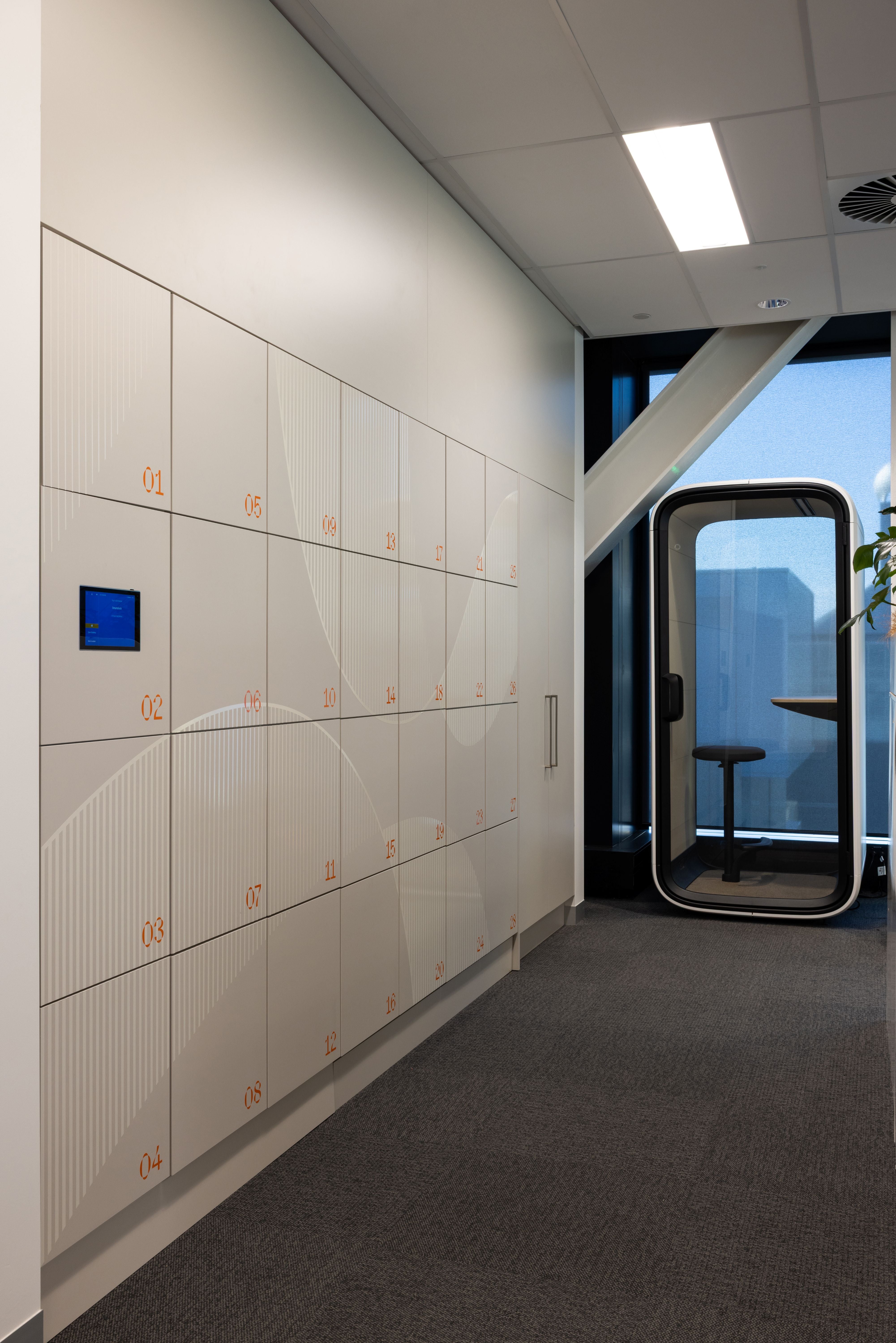 Modern office interior with lockers and a glass partition.