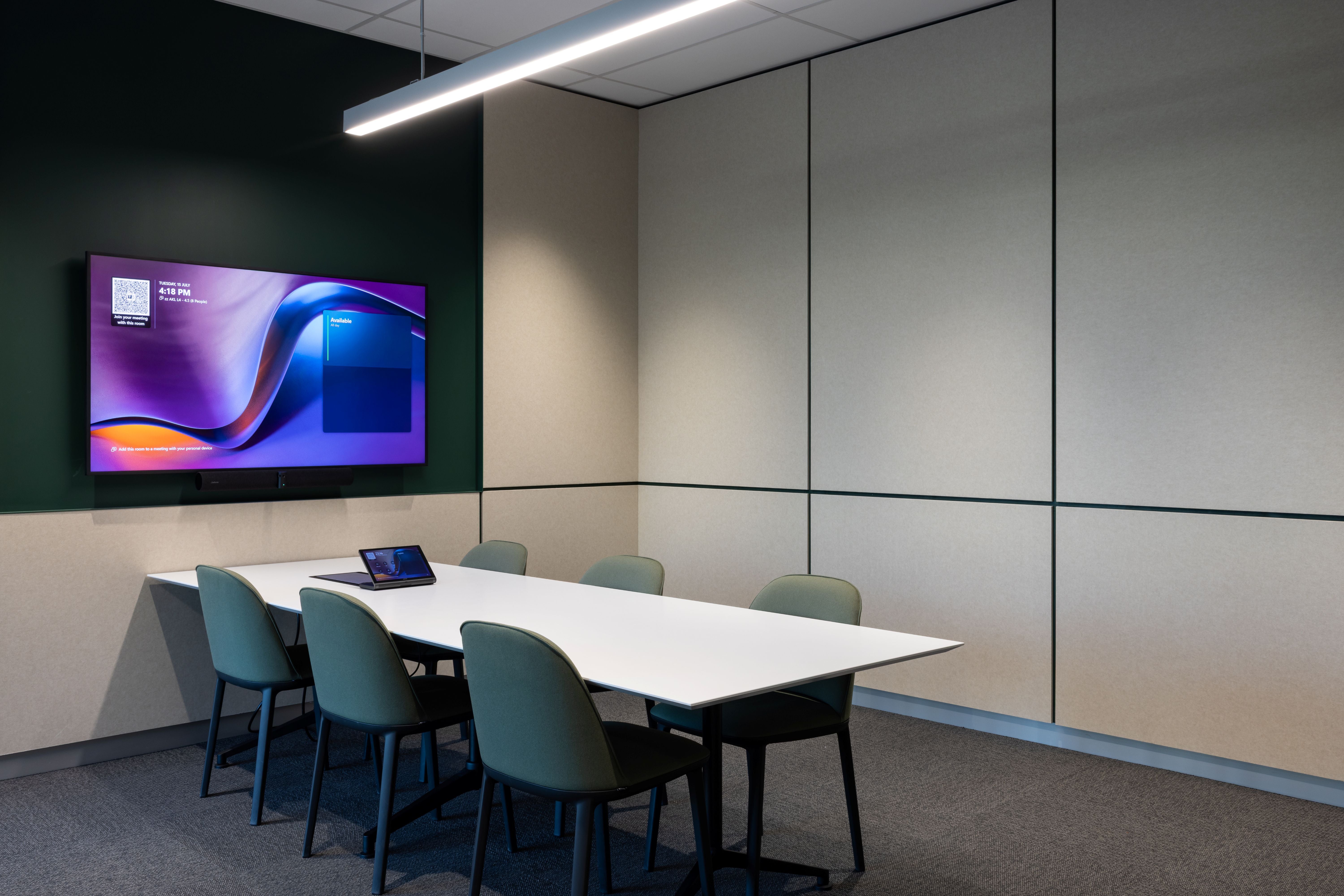 Modern conference room with a large screen displaying a colorful graphic, surrounded by chairs and tables.