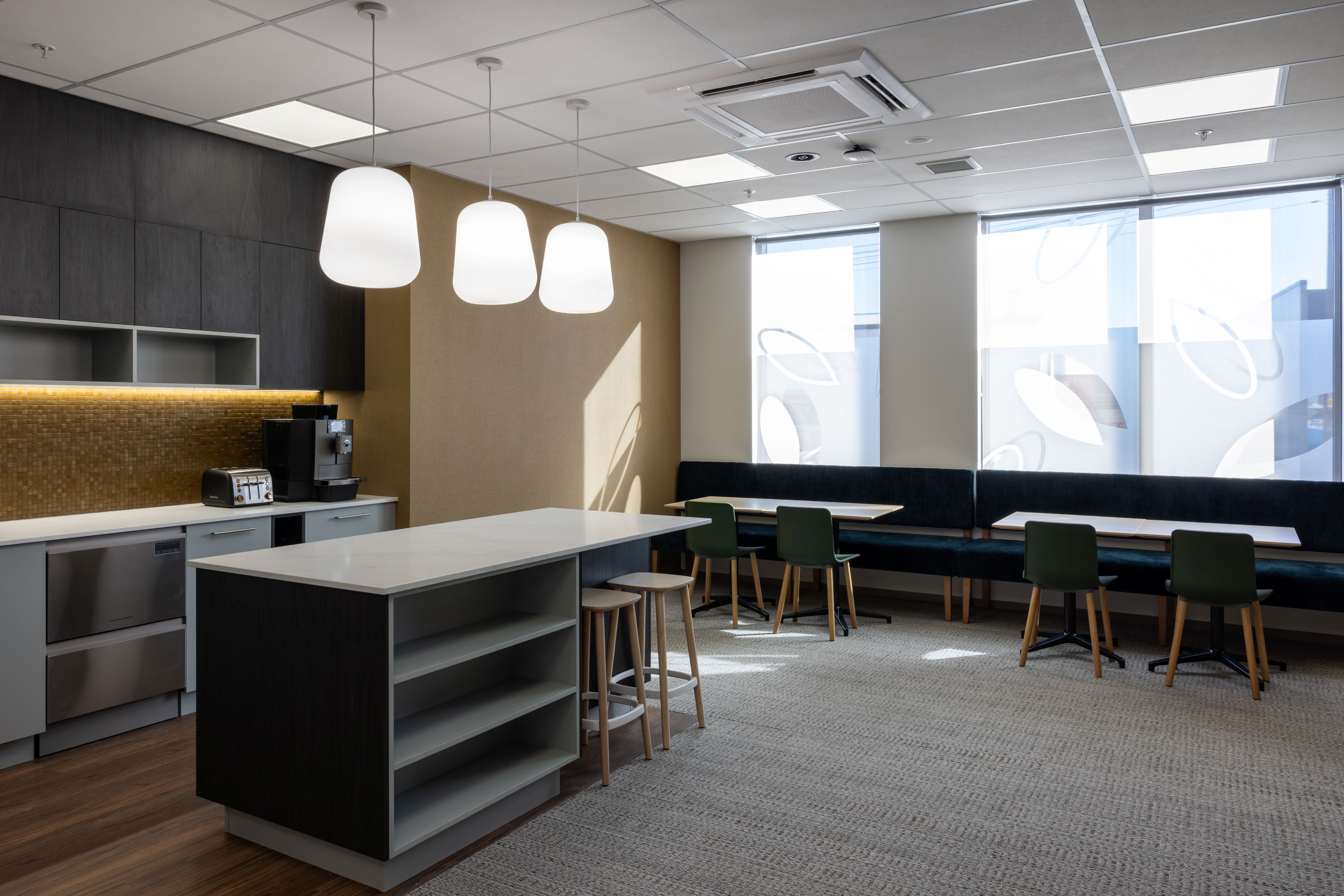 Modern office break room with kitchenette and seating area