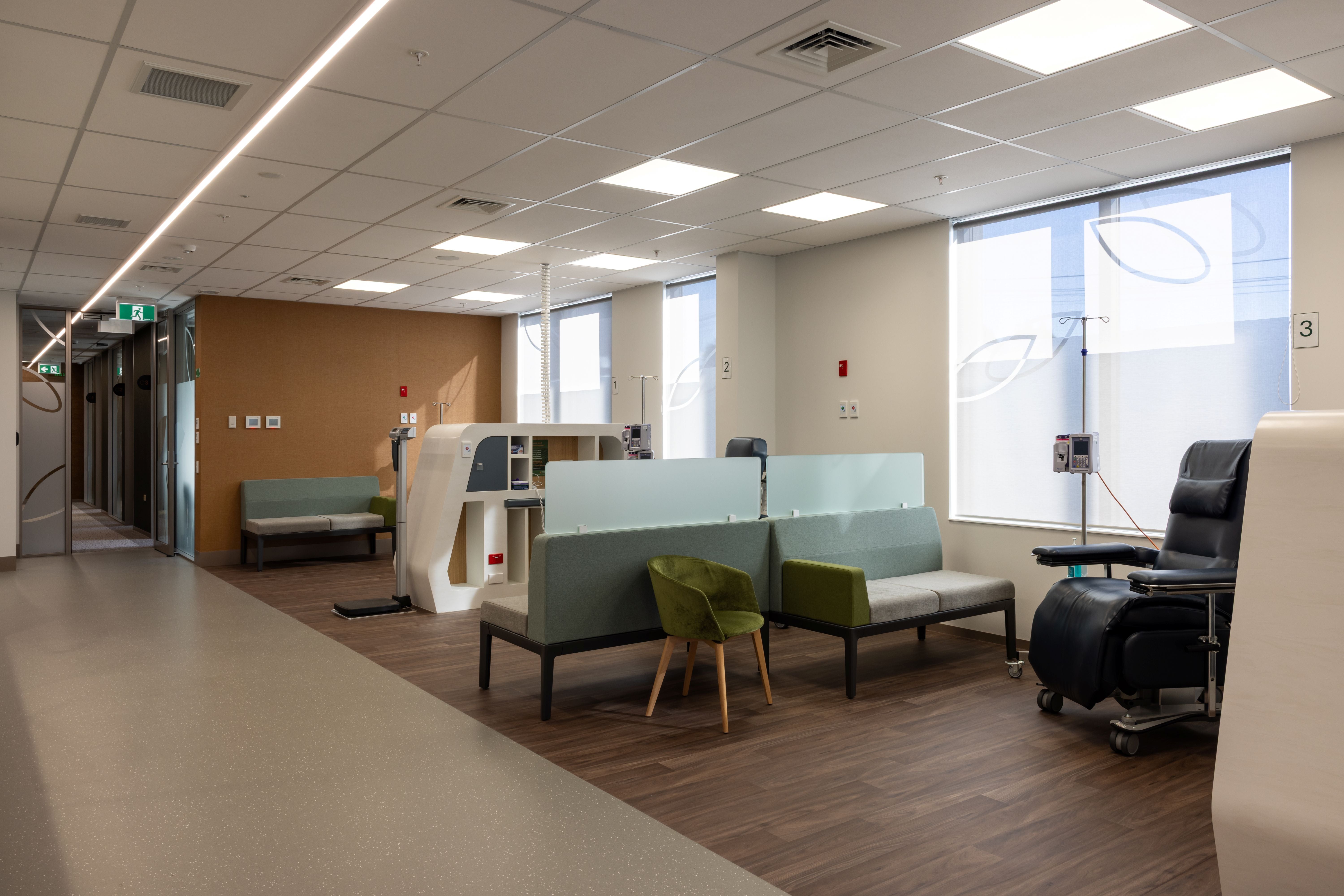 Modern office or waiting area with green chairs, a desk, and large windows.