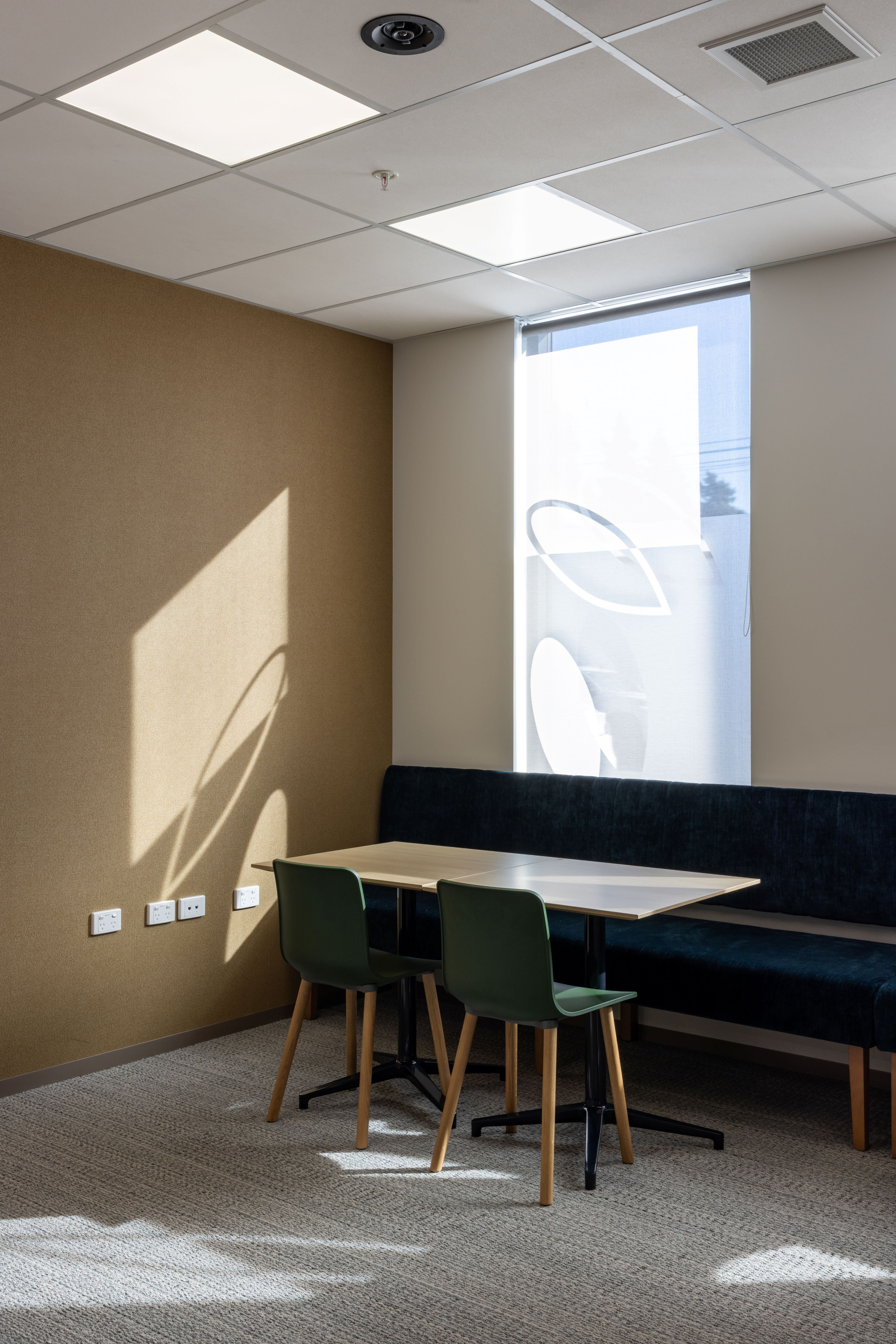 Modern office break room with table, chairs, and bench.