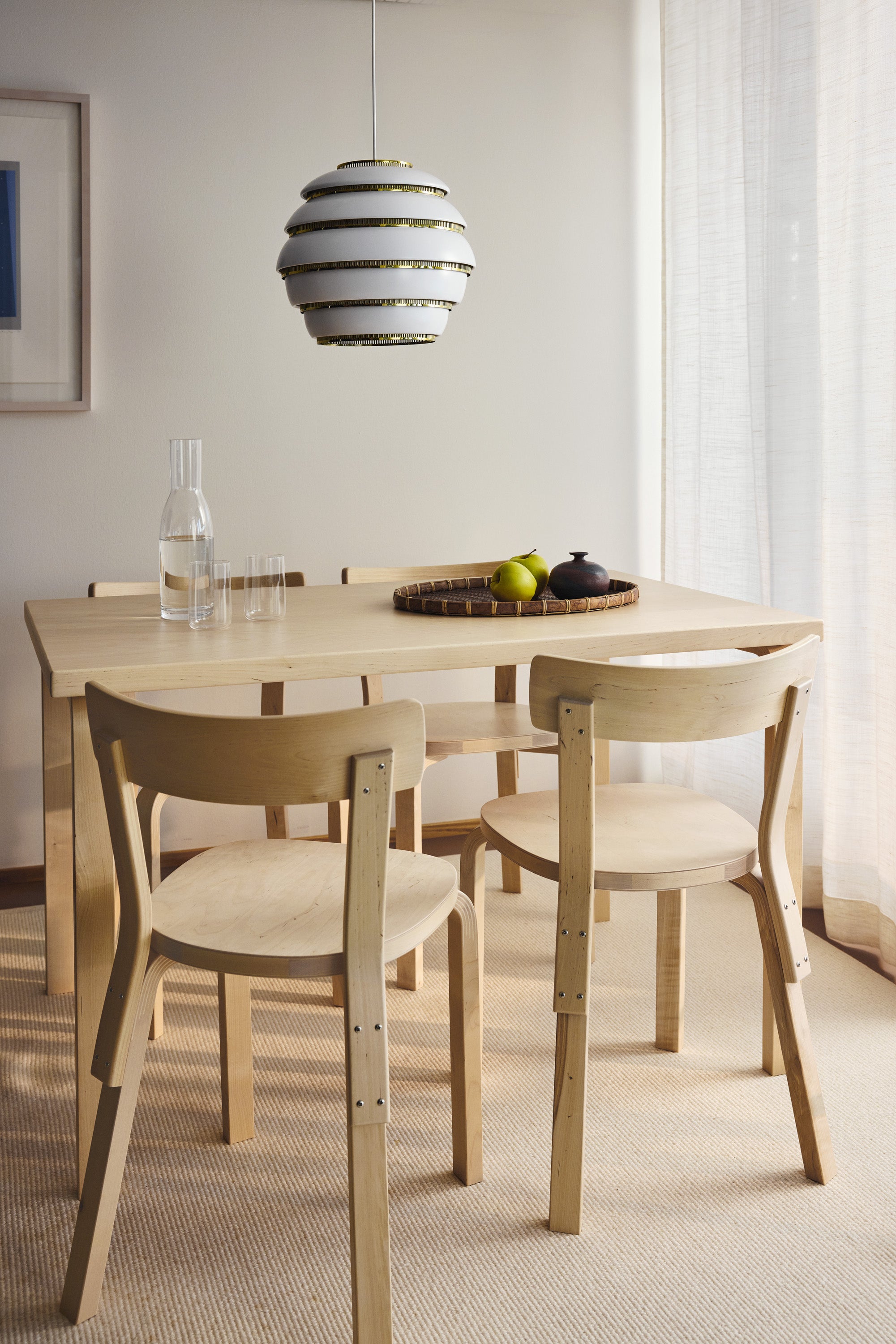 Dining area with wooden table and chairs, modern pendant light, and framed artwork on the wall.