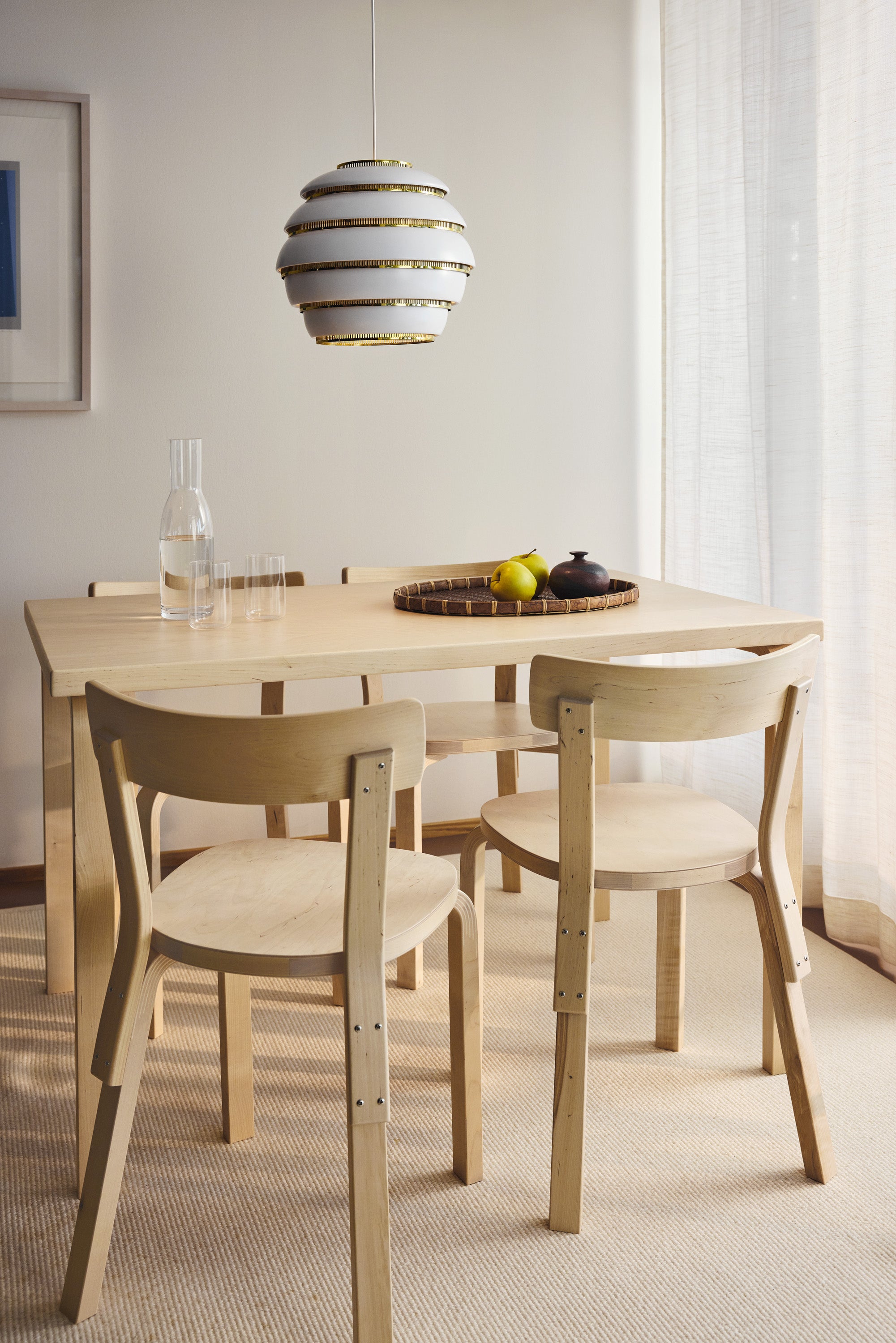 Dining room with wooden table and chairs, modern pendant light, and framed artwork.