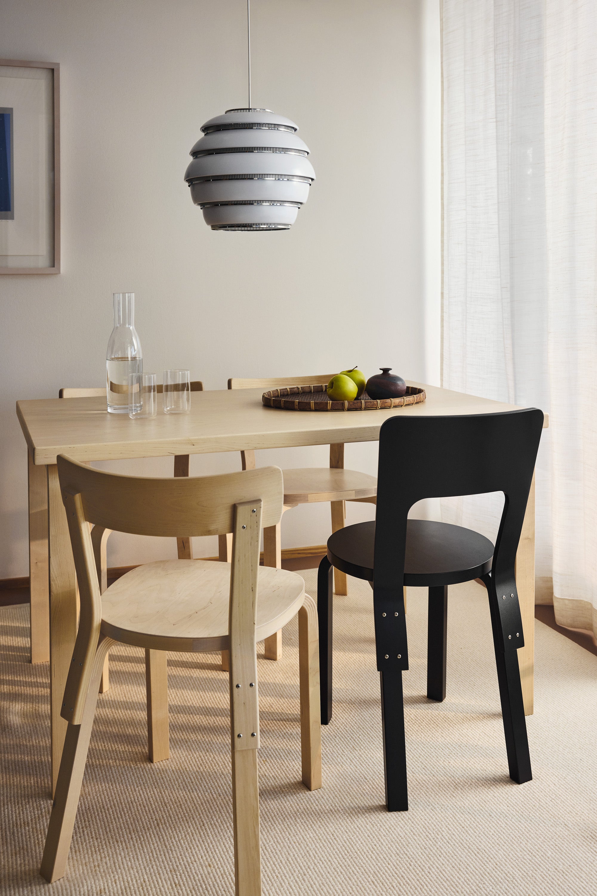 Dining area with a light wooden table and chairs, including a black chair.