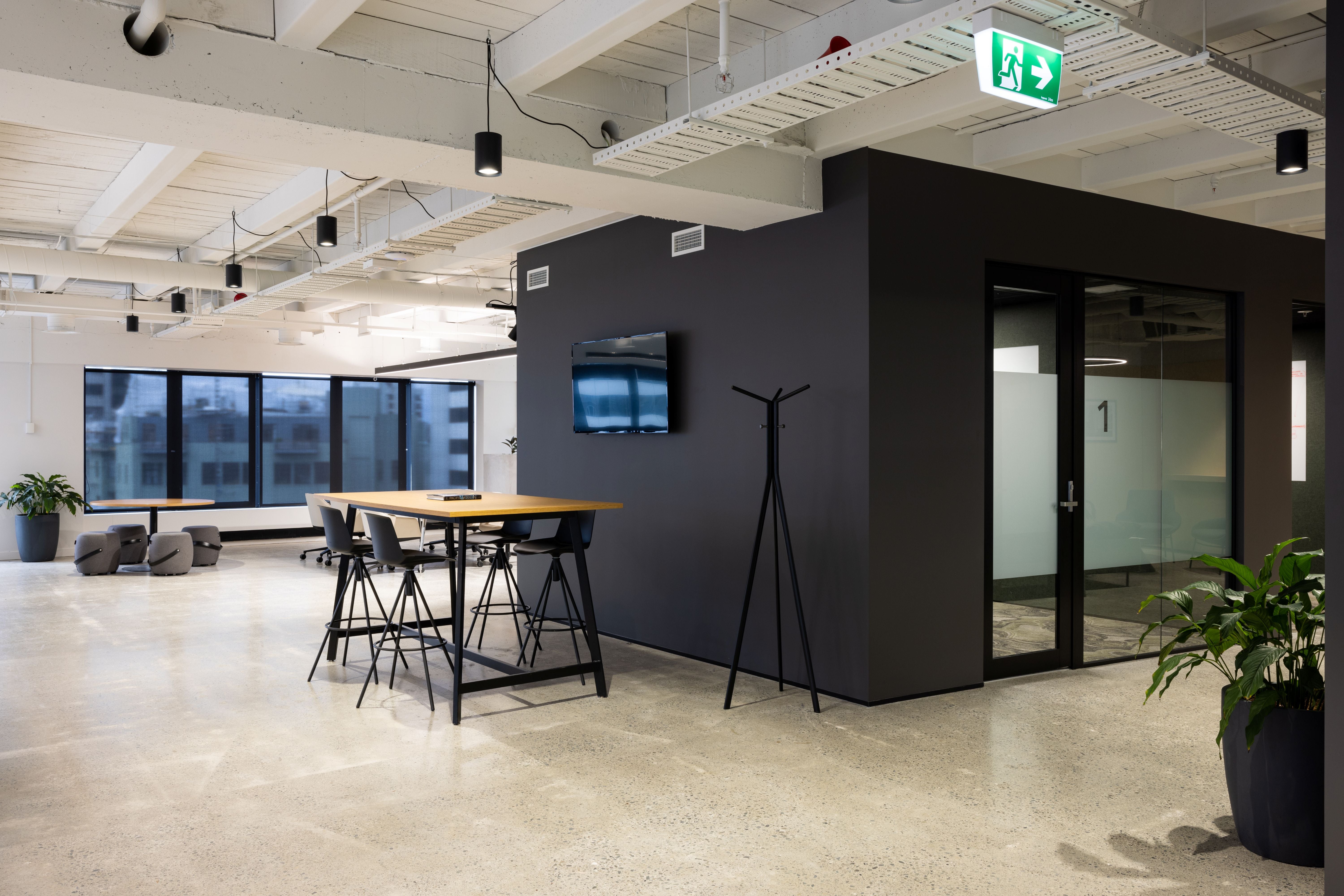 Modern office space with a black wall, table, and chairs.