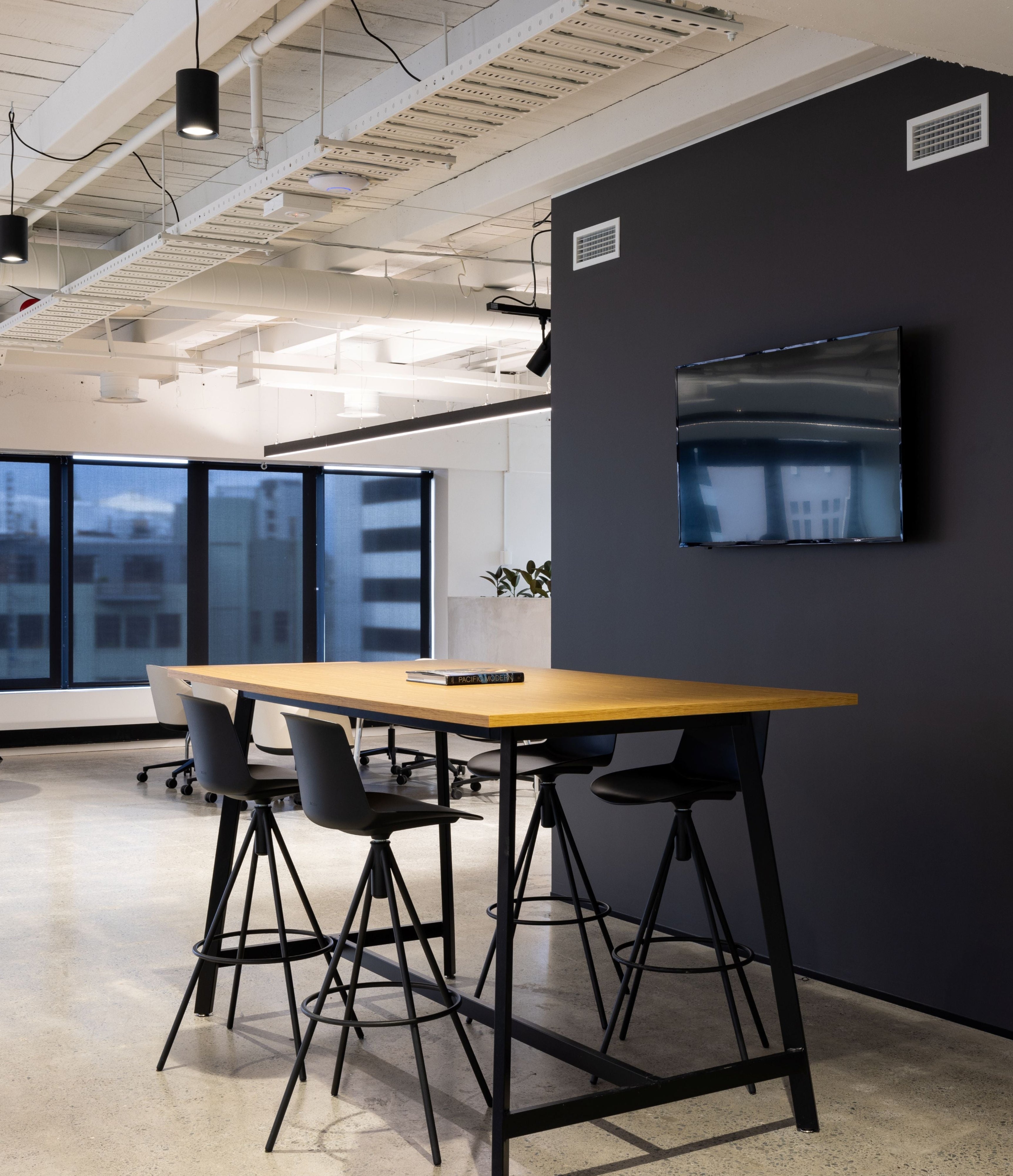 Modern office space with a conference table and chairs, large windows, and a coat rack.