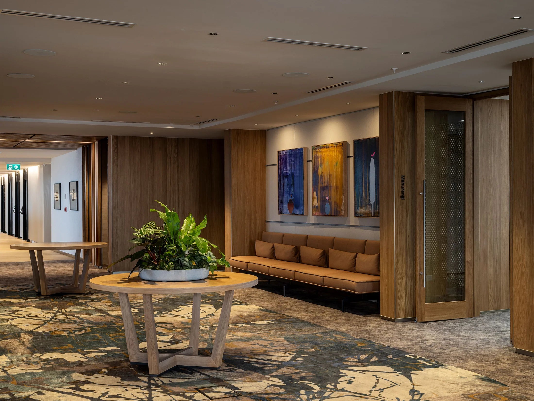 Modern interior with a round wooden table, sofa, and decorative plants.