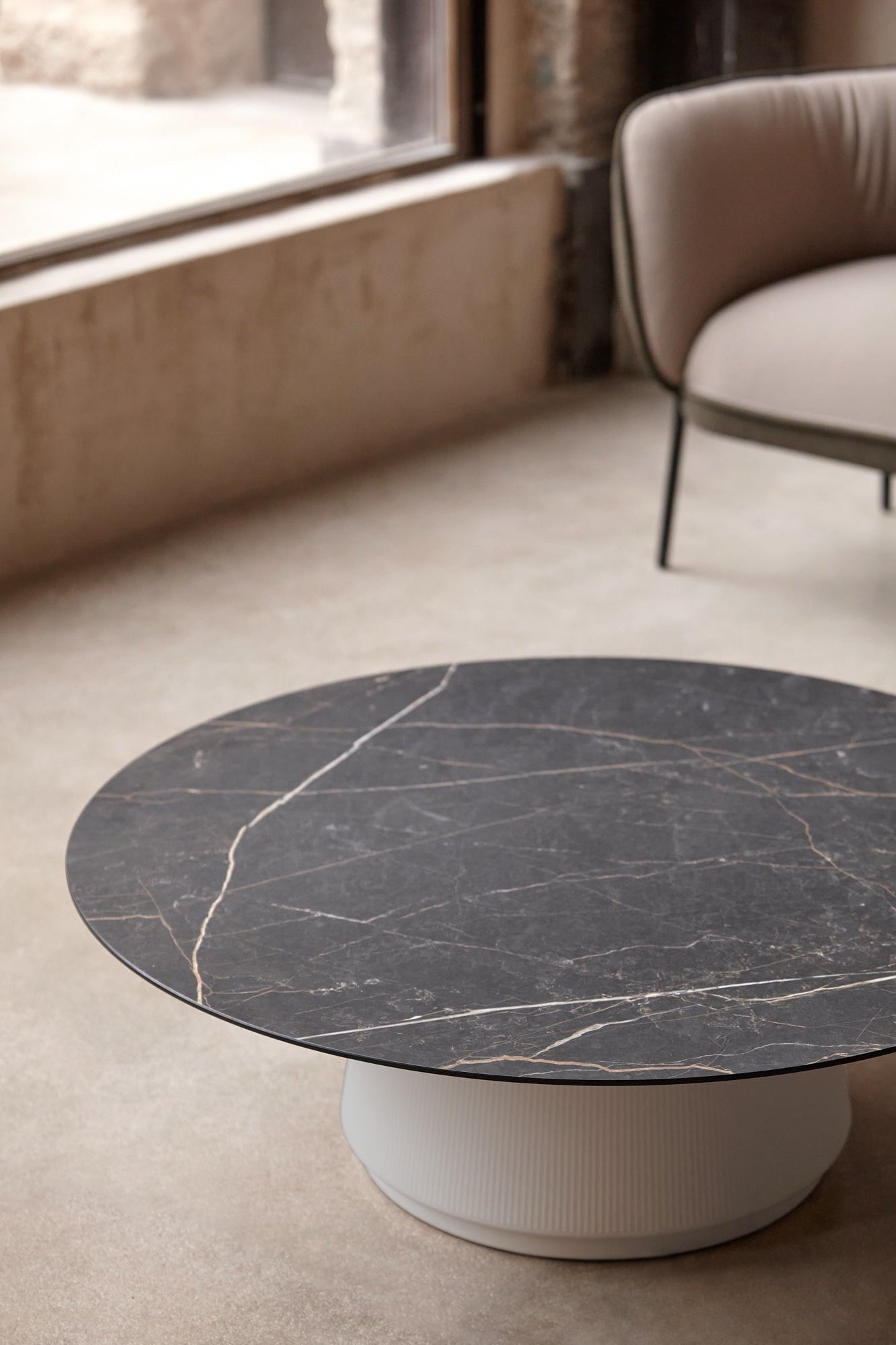 Round marble coffee table with a white base in a modern living room.