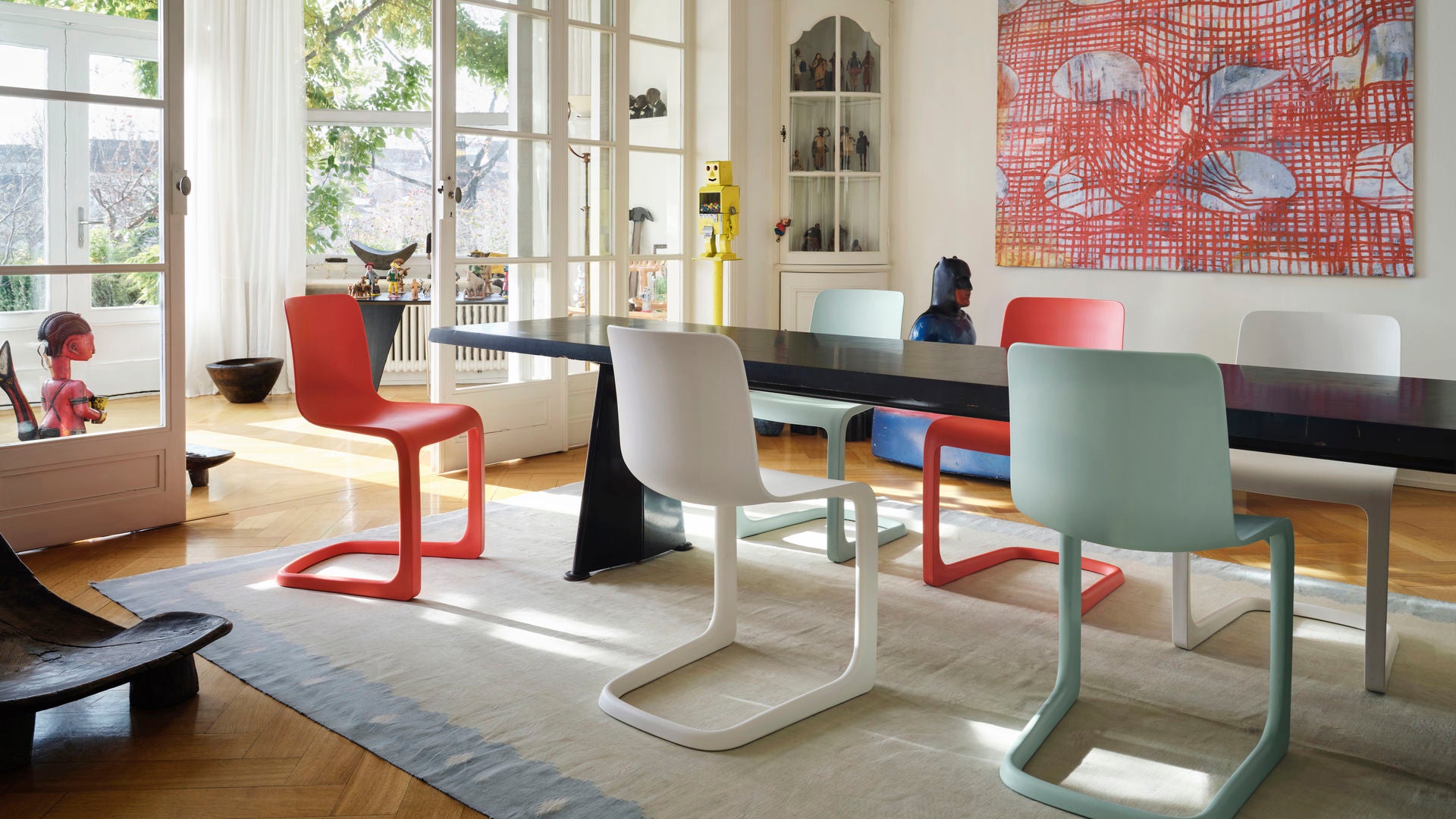 Modern dining room with colorful chairs and a large window.