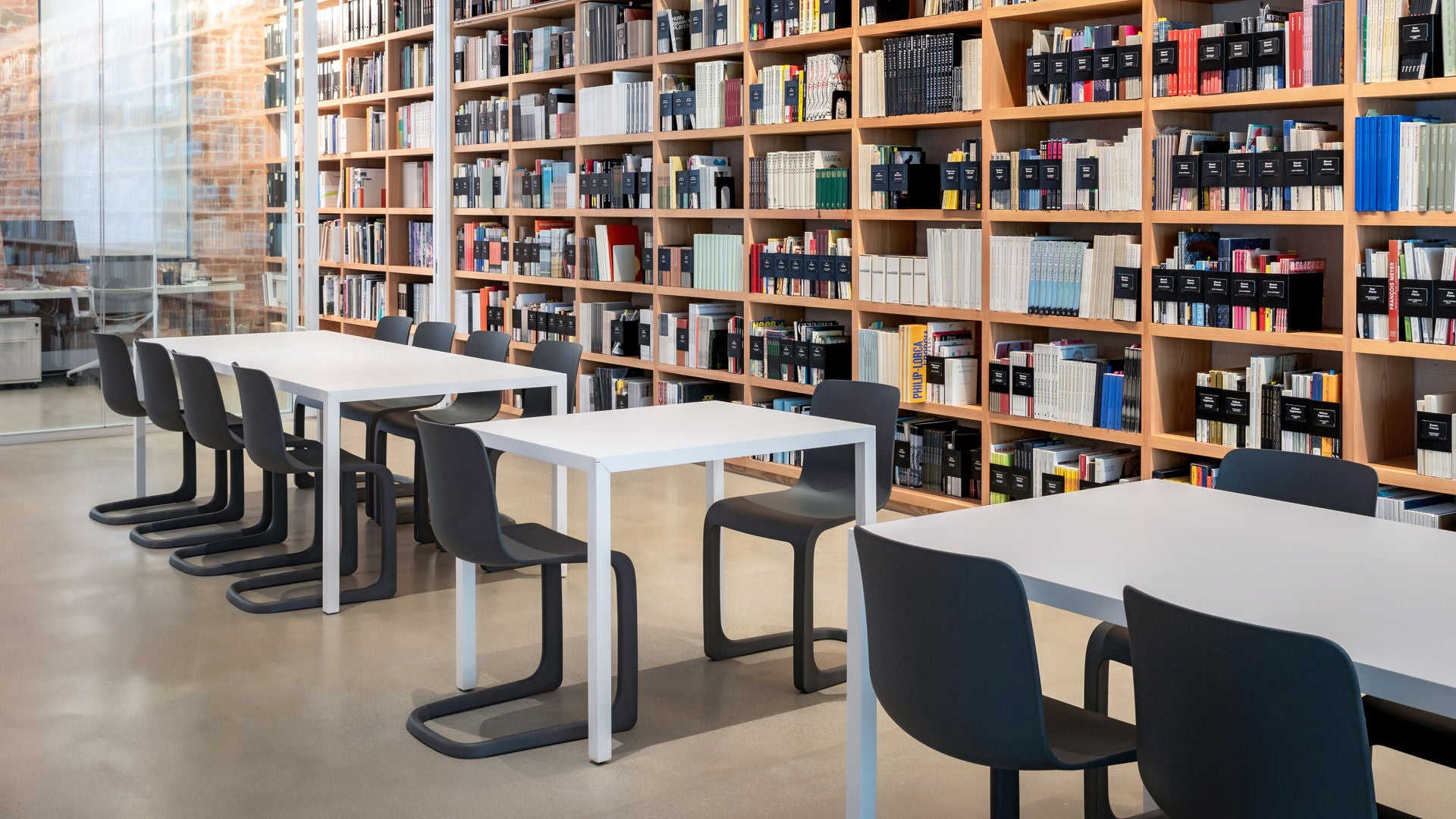 Library with tables and chairs in a room filled with bookshelves.