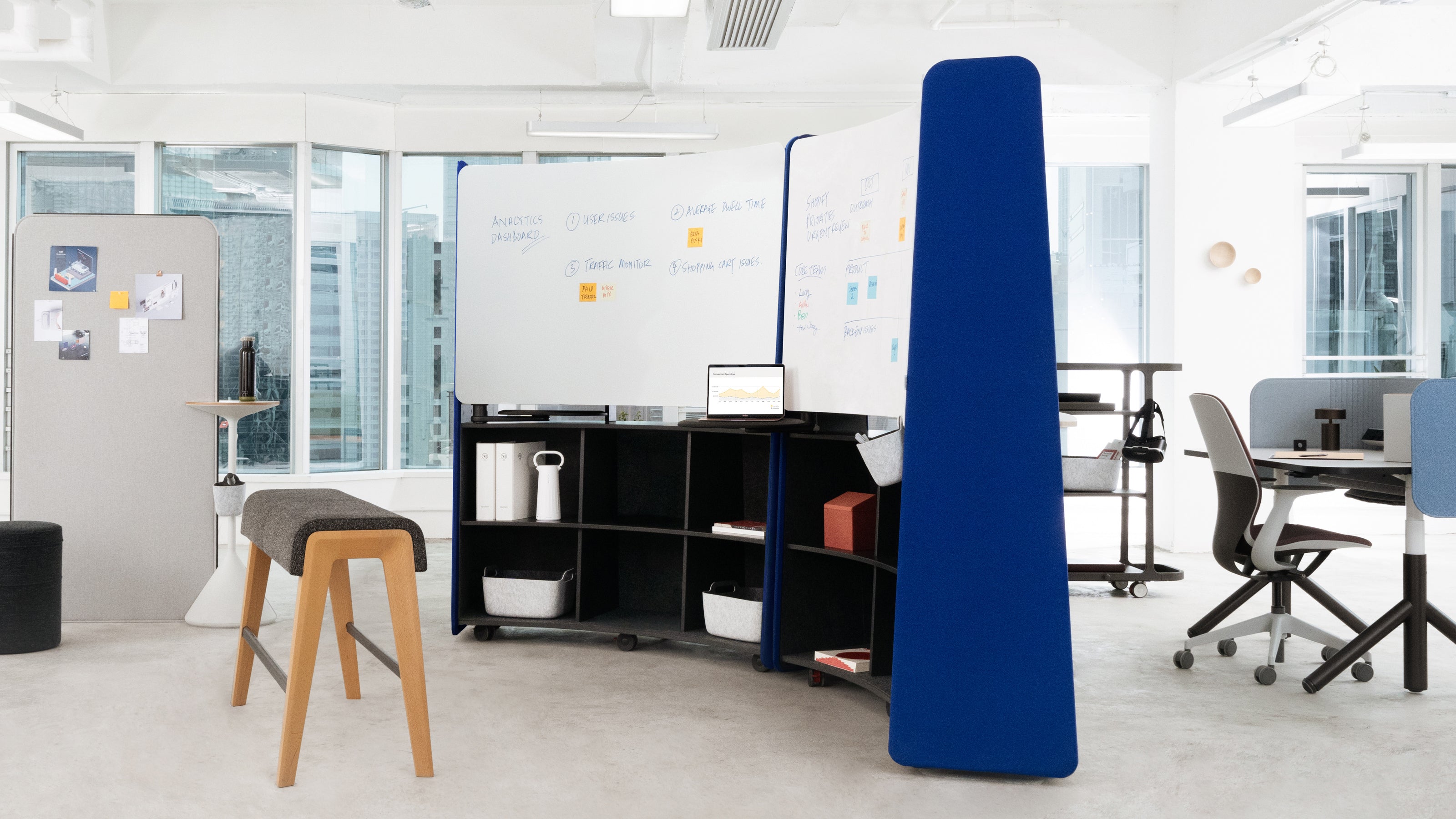 Modern office space with a blue partition, desk, and chairs.