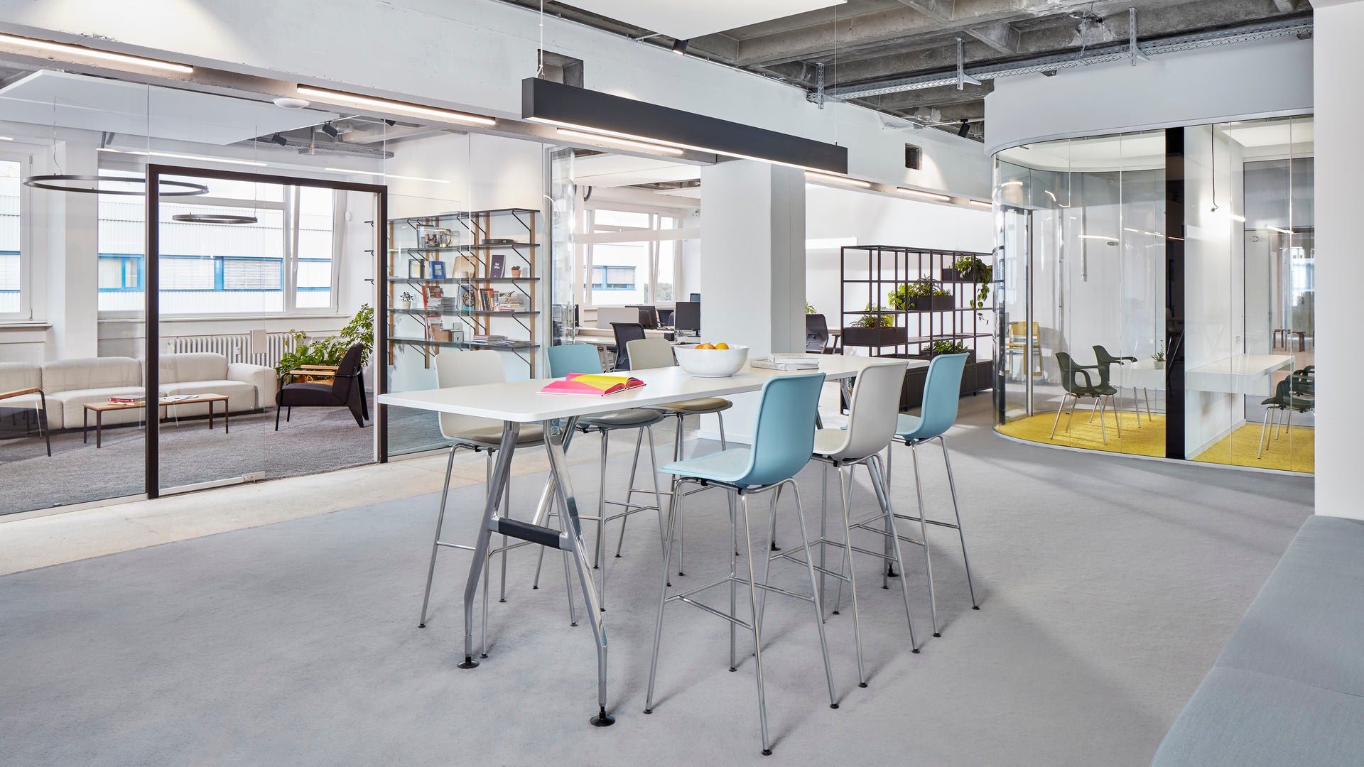 Modern office space with a long white table and blue chairs.