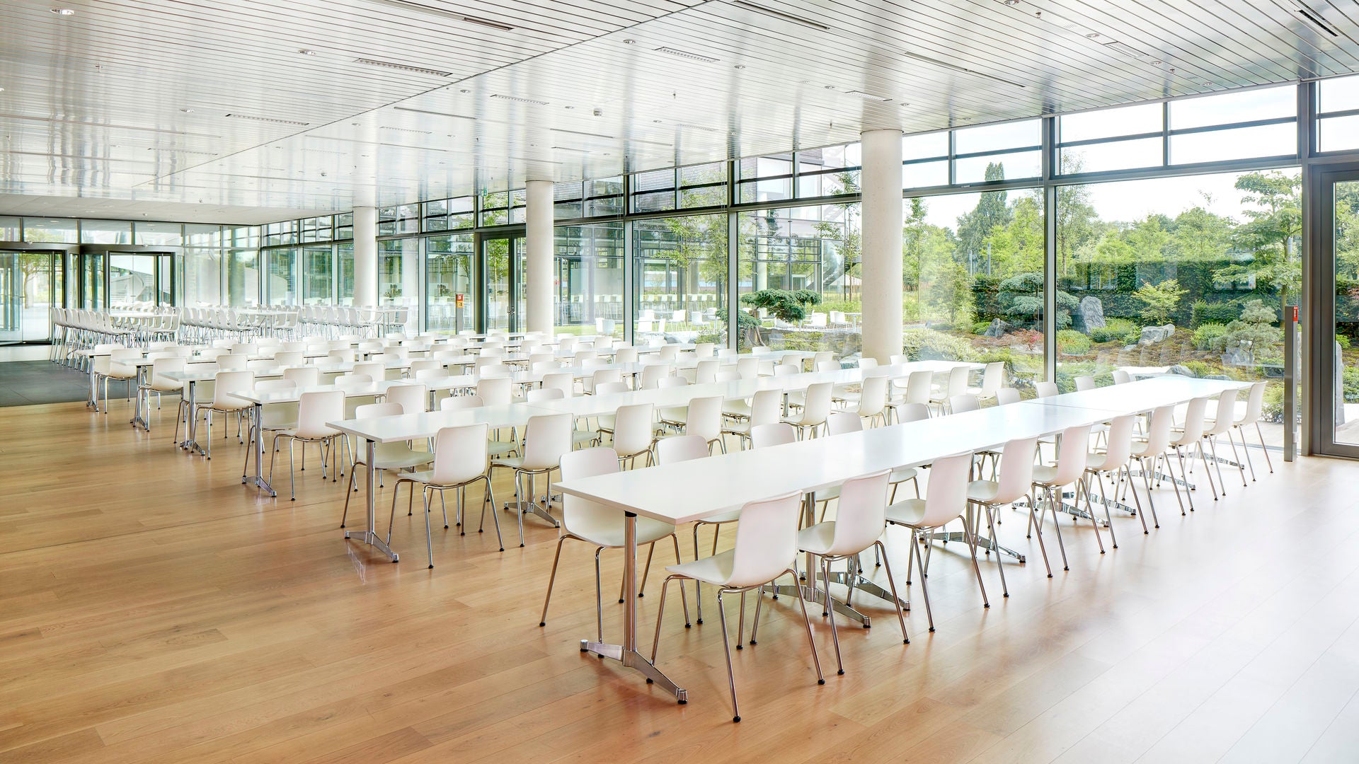 Modern conference room with white tables and chairs in a well-lit space.