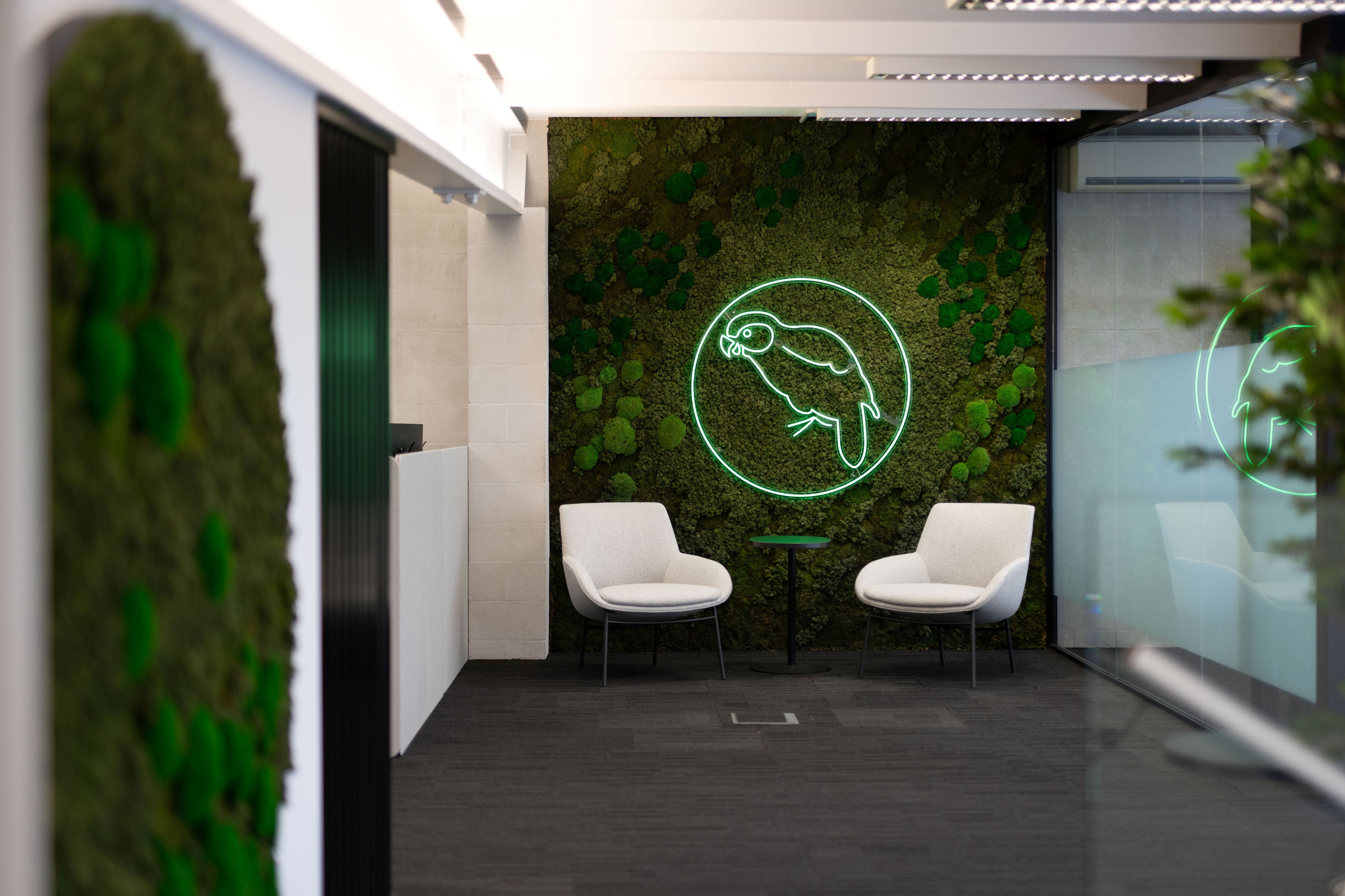 Modern office interior with green neon sign on moss wall