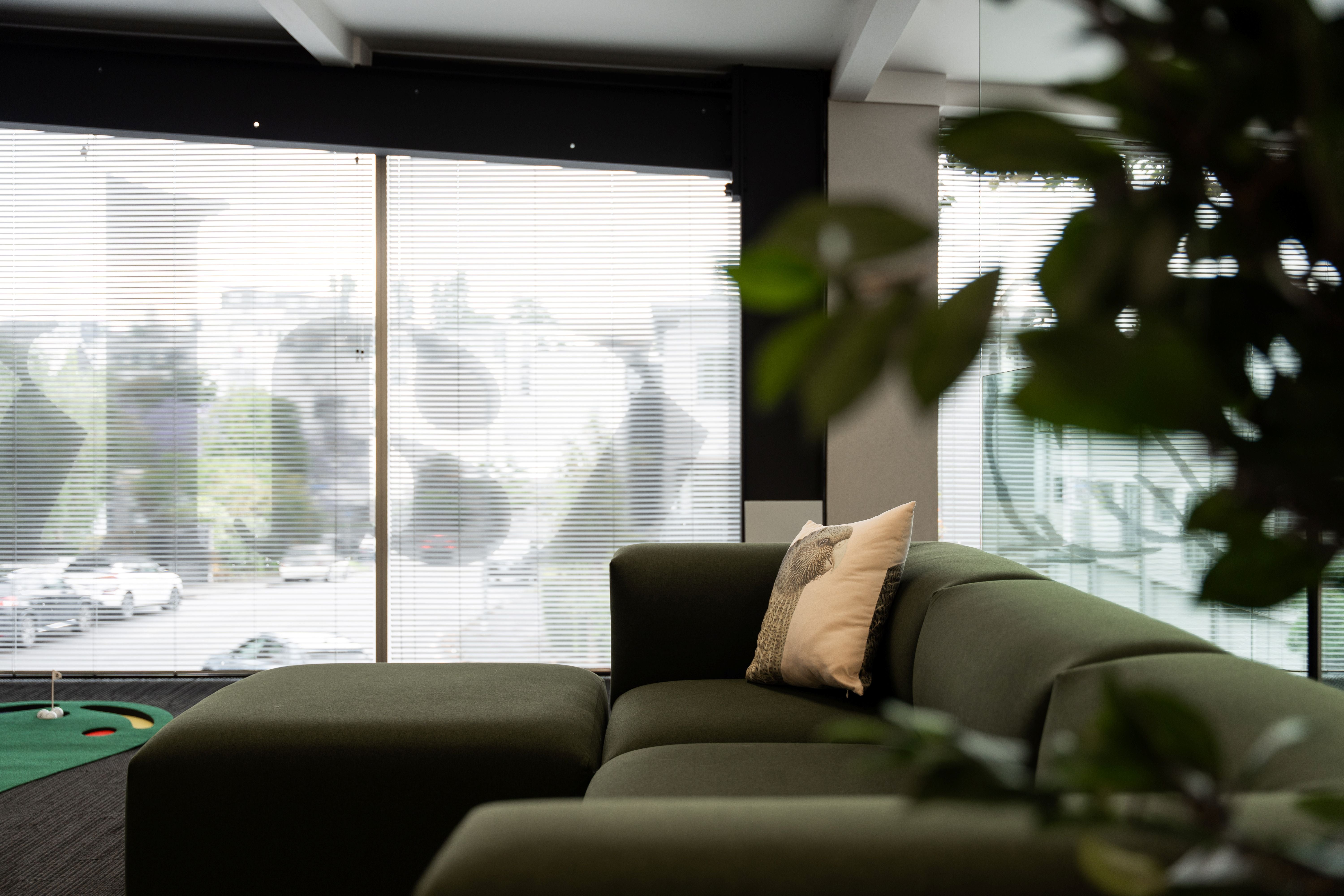 Modern living room with a green sofa and large windows.