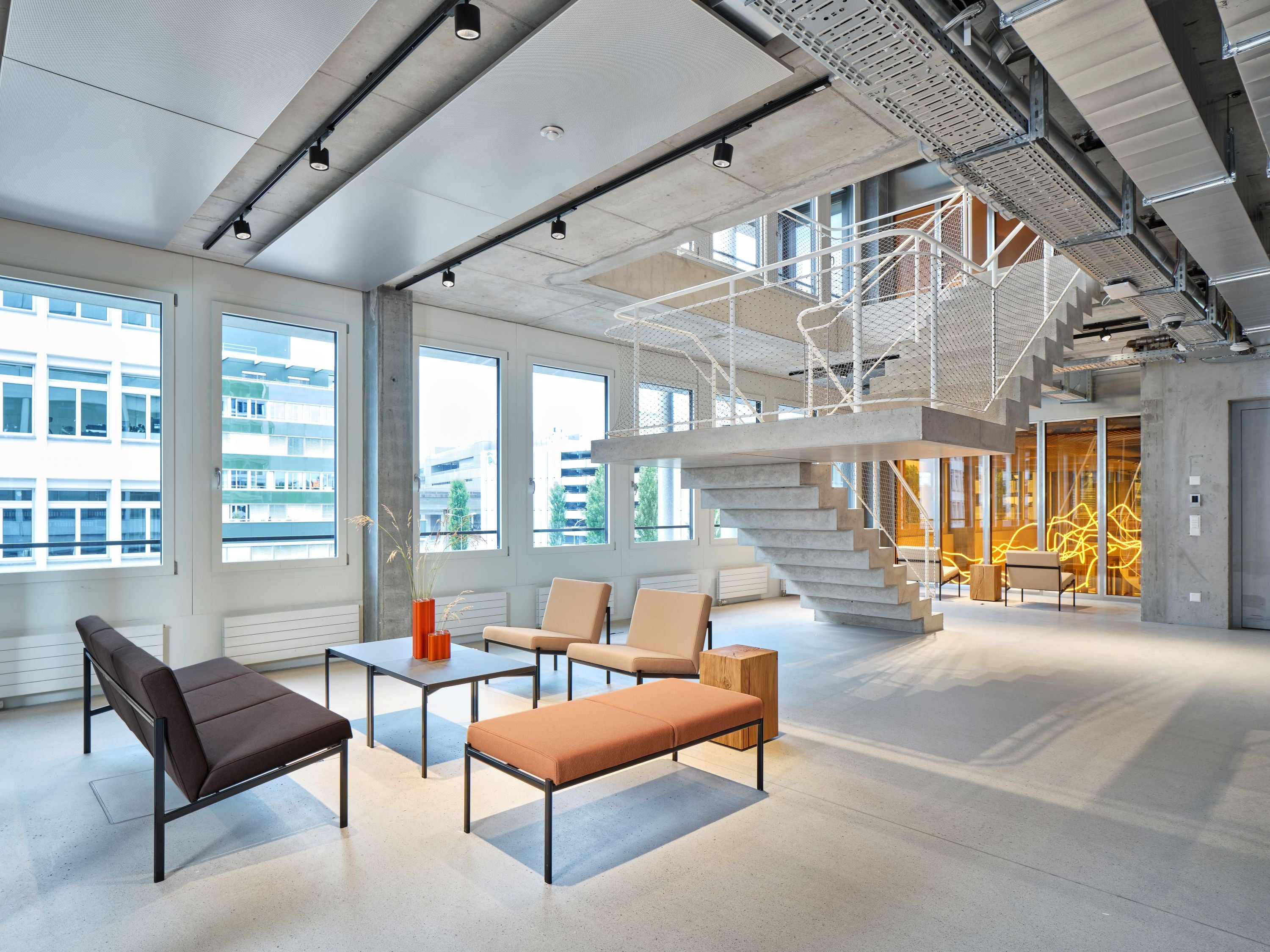 Modern office space with a staircase, couches, and coffee table.