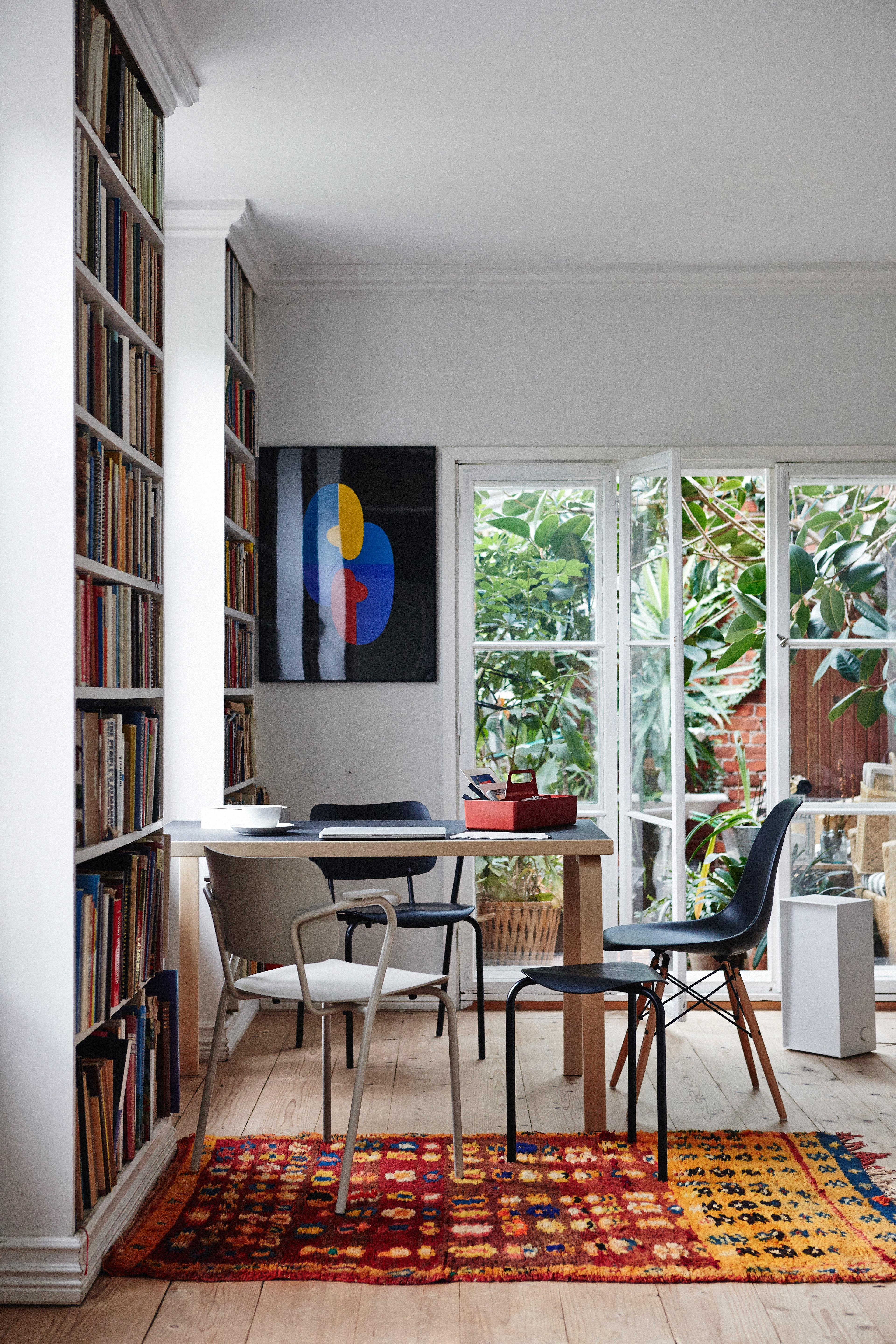 Modern home office with bookshelves, a desk, and colorful rug.