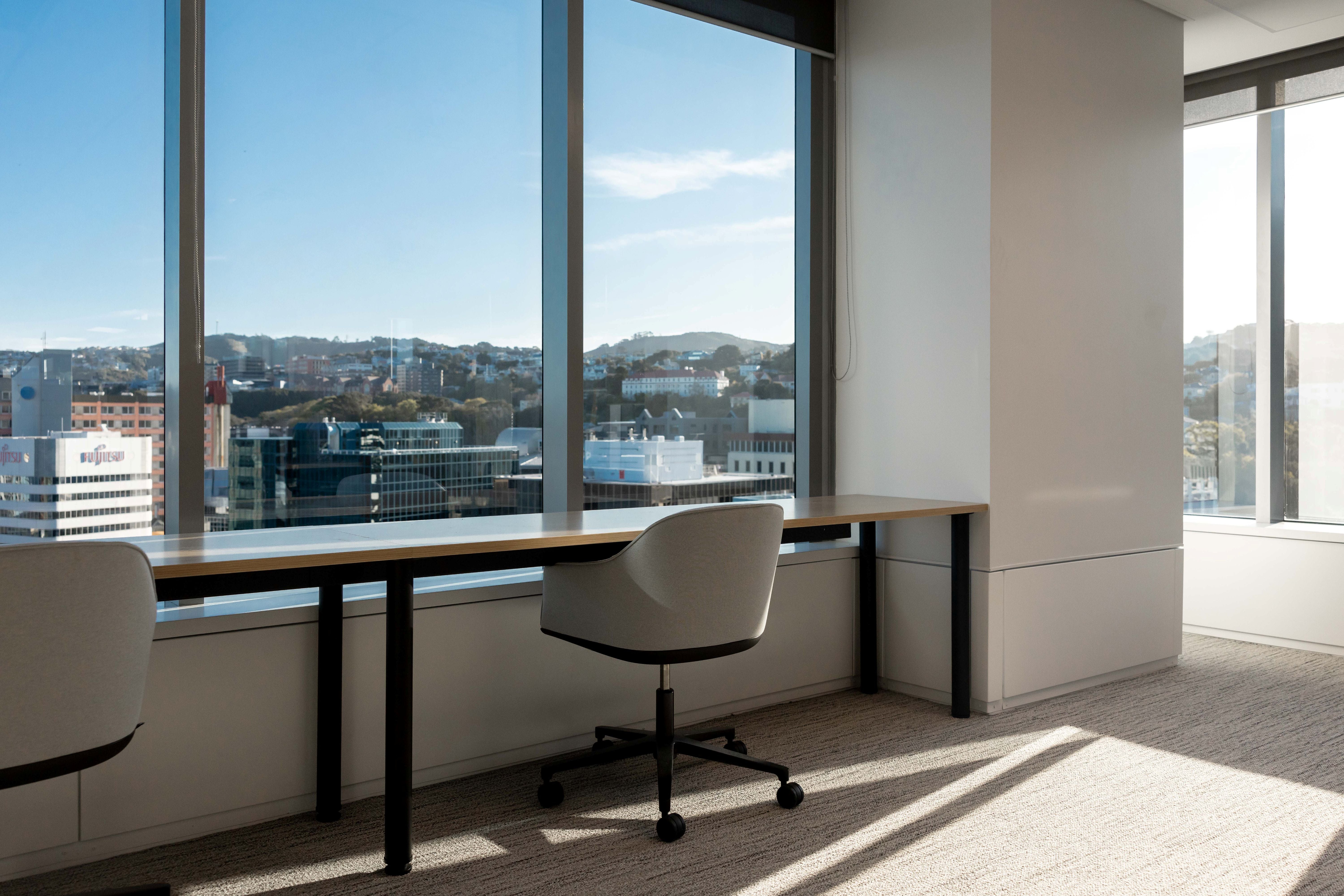 Modern office desk with chair by large windows with a cityscape view