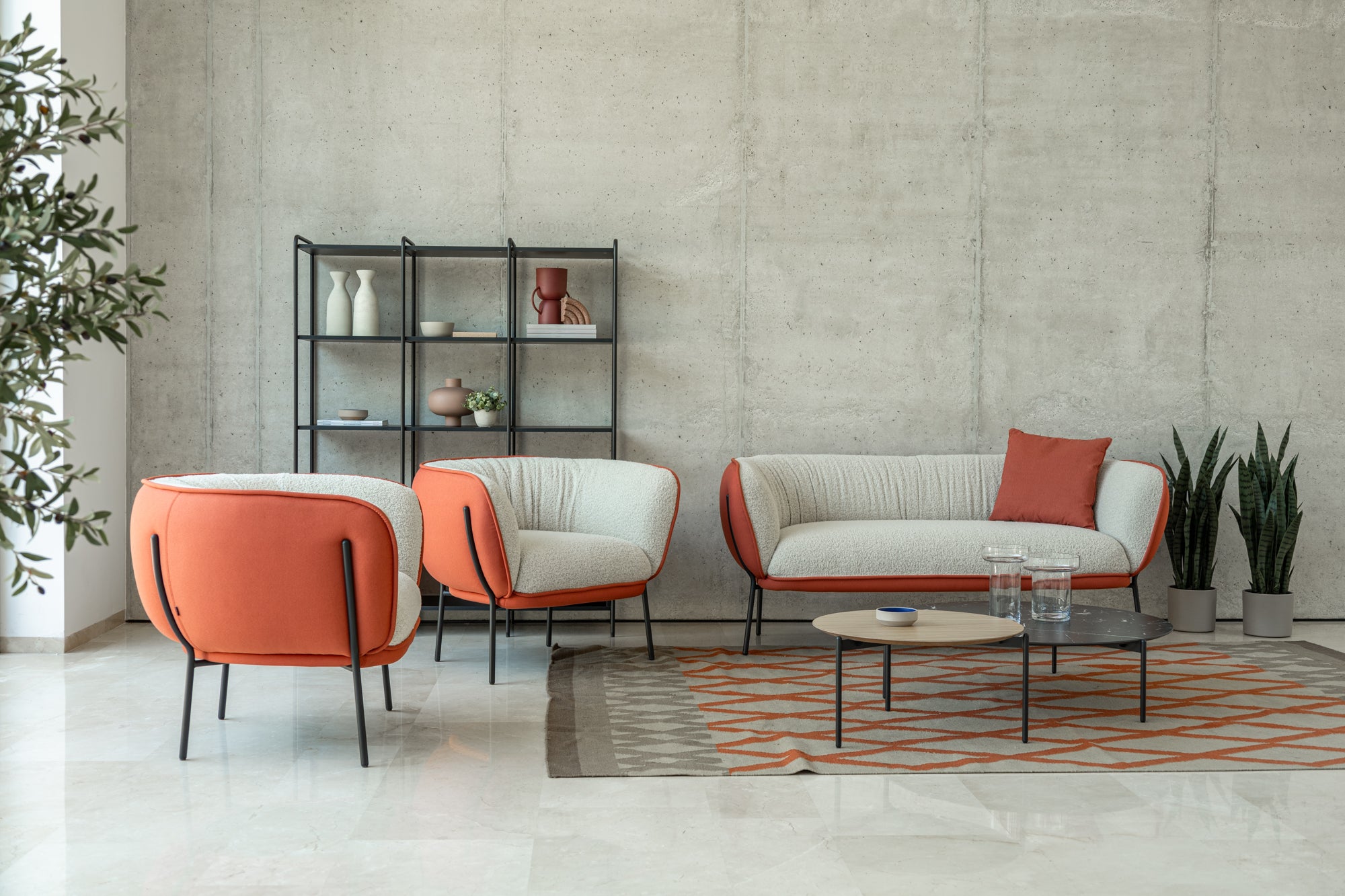 Modern living room with orange and white furniture against a concrete wall.
