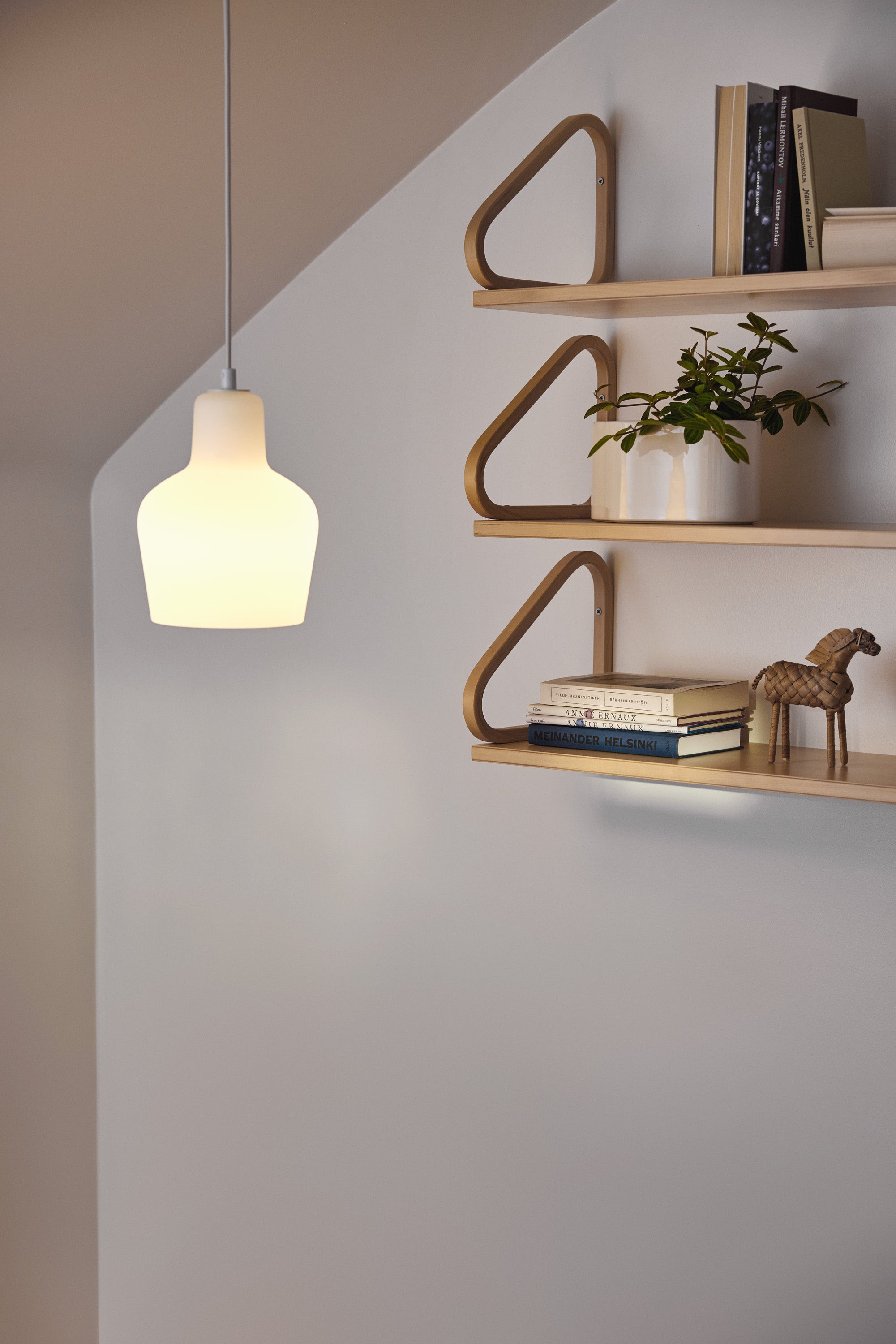 Modern wall-mounted shelves with a pendant light against a neutral wall.