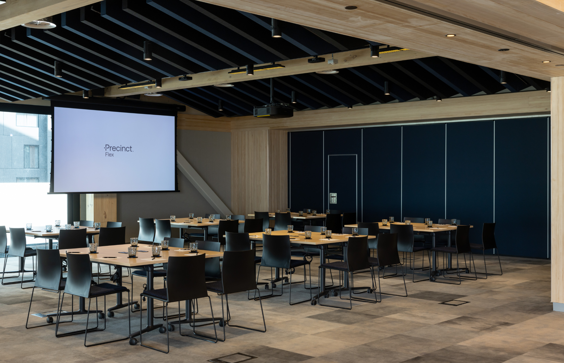 Modern conference room with tables, chairs, and a large screen displaying 'Project'.