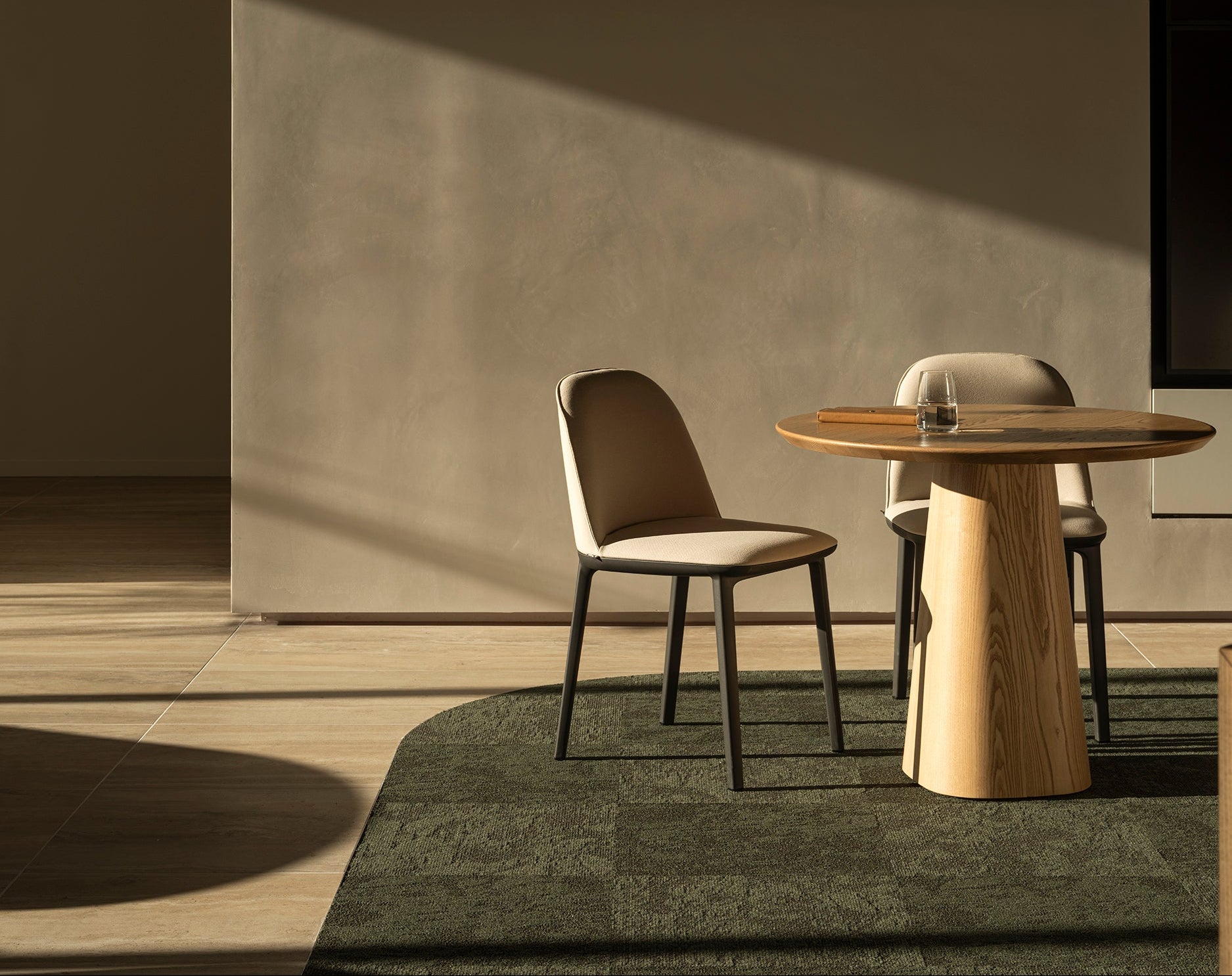 Modern dining area with a round table and chairs in a minimalistic setting.