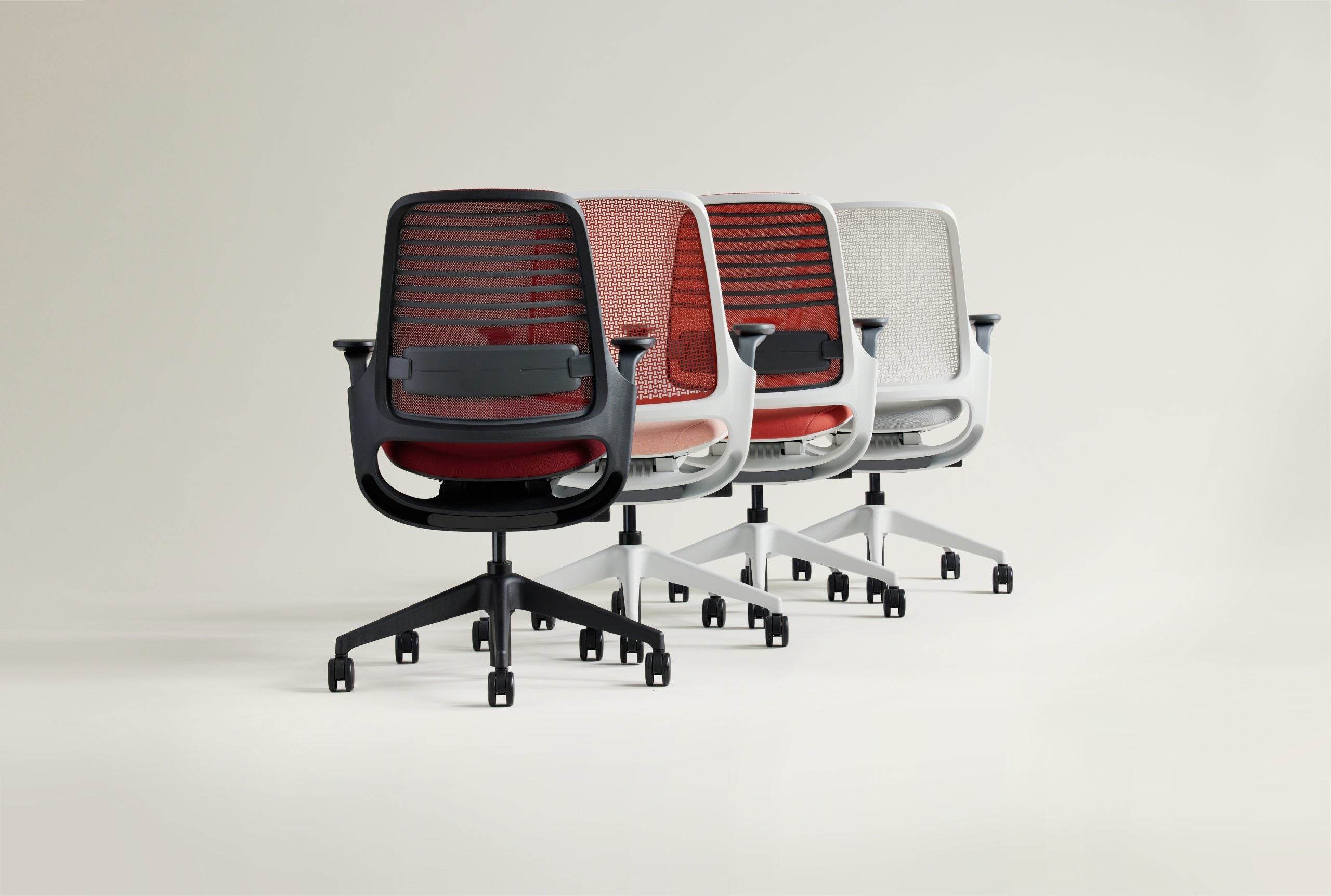 Four office chairs with different colored backrests on a white background