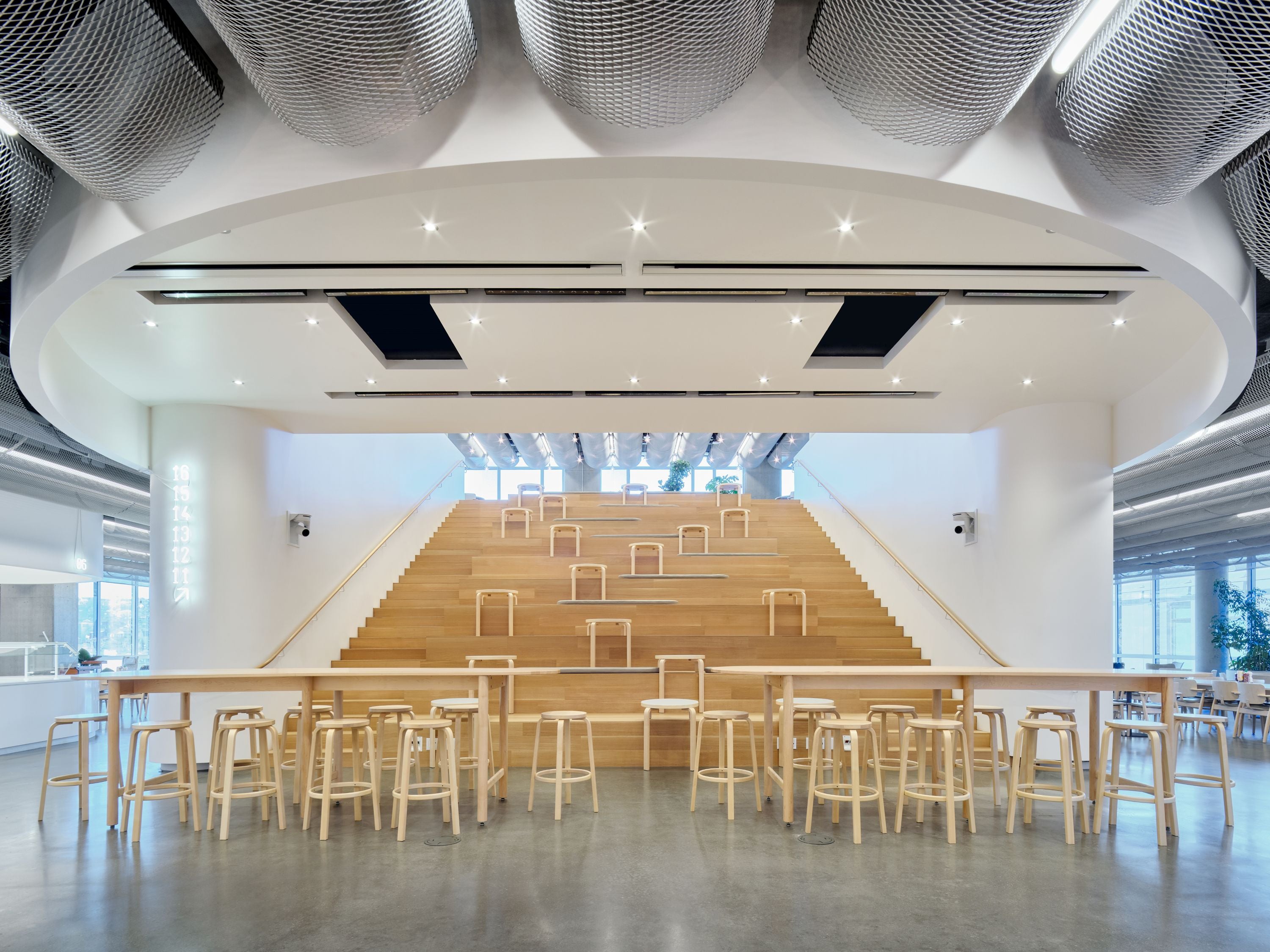 Modern interior with wooden tables and stools in a large room with high ceilings.