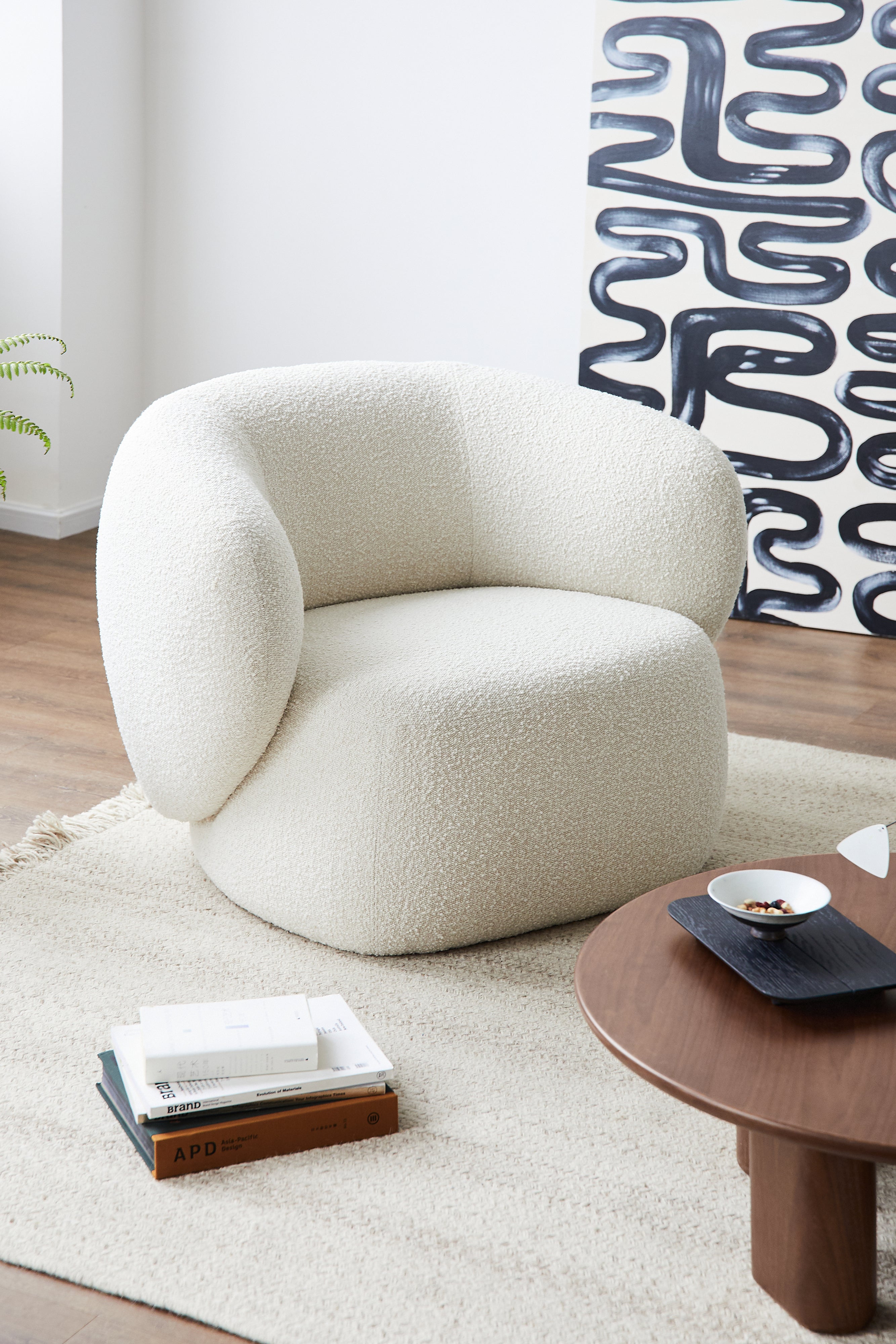 White textured armchair in a modern living room with a wooden coffee table and abstract wall art.