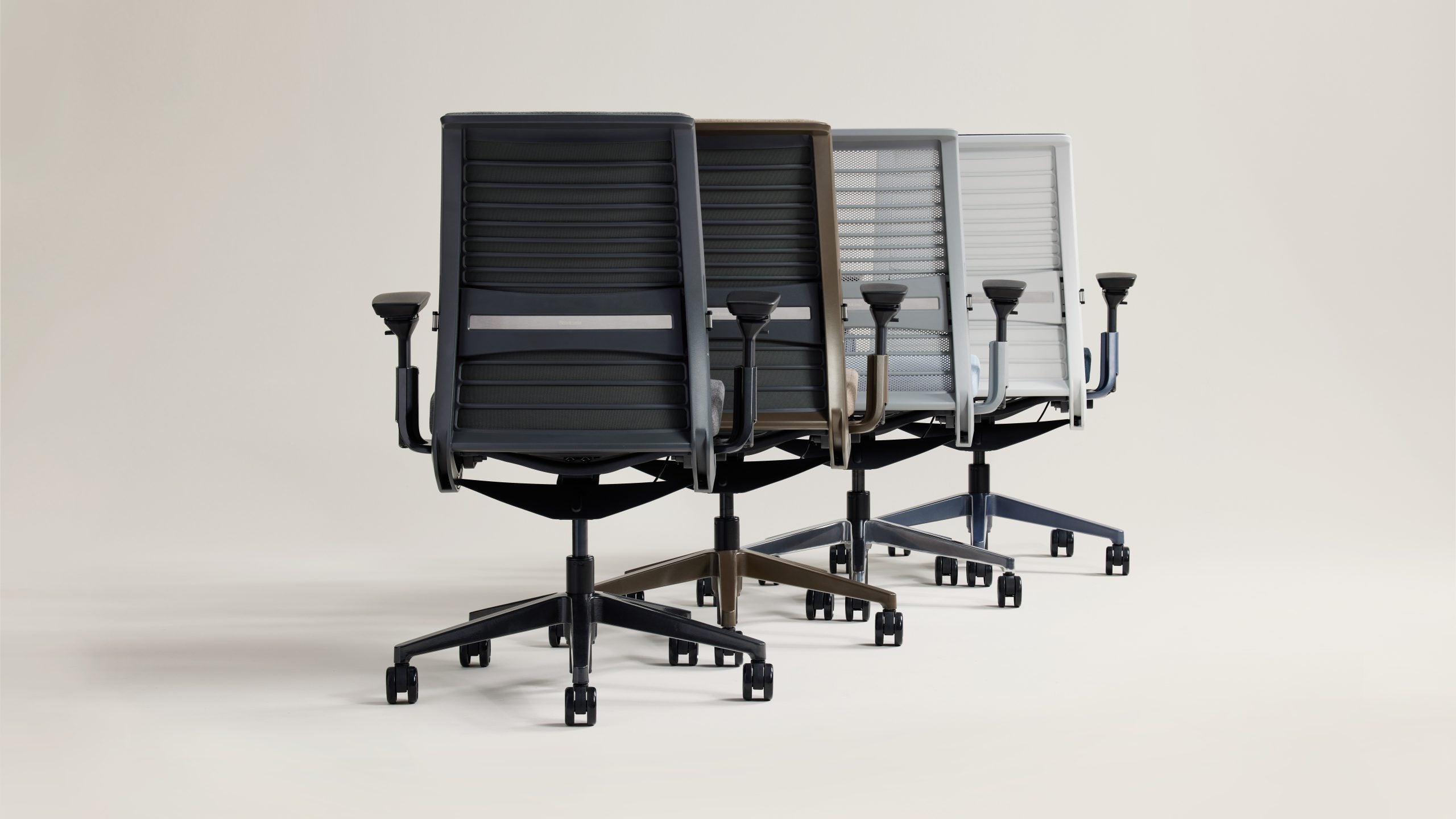 Three office chairs in black, gray, and white on a light background