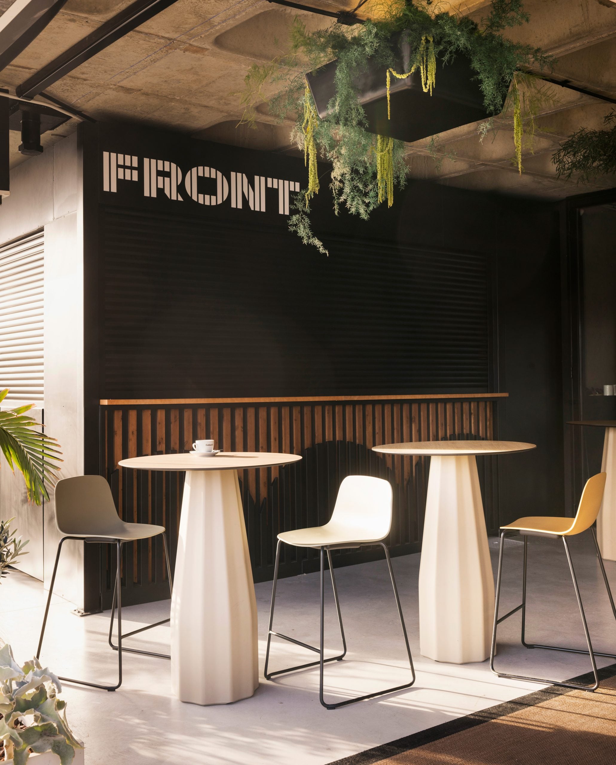 Modern cafe interior with tables, chairs, and 'FRONT' branding on the wall.