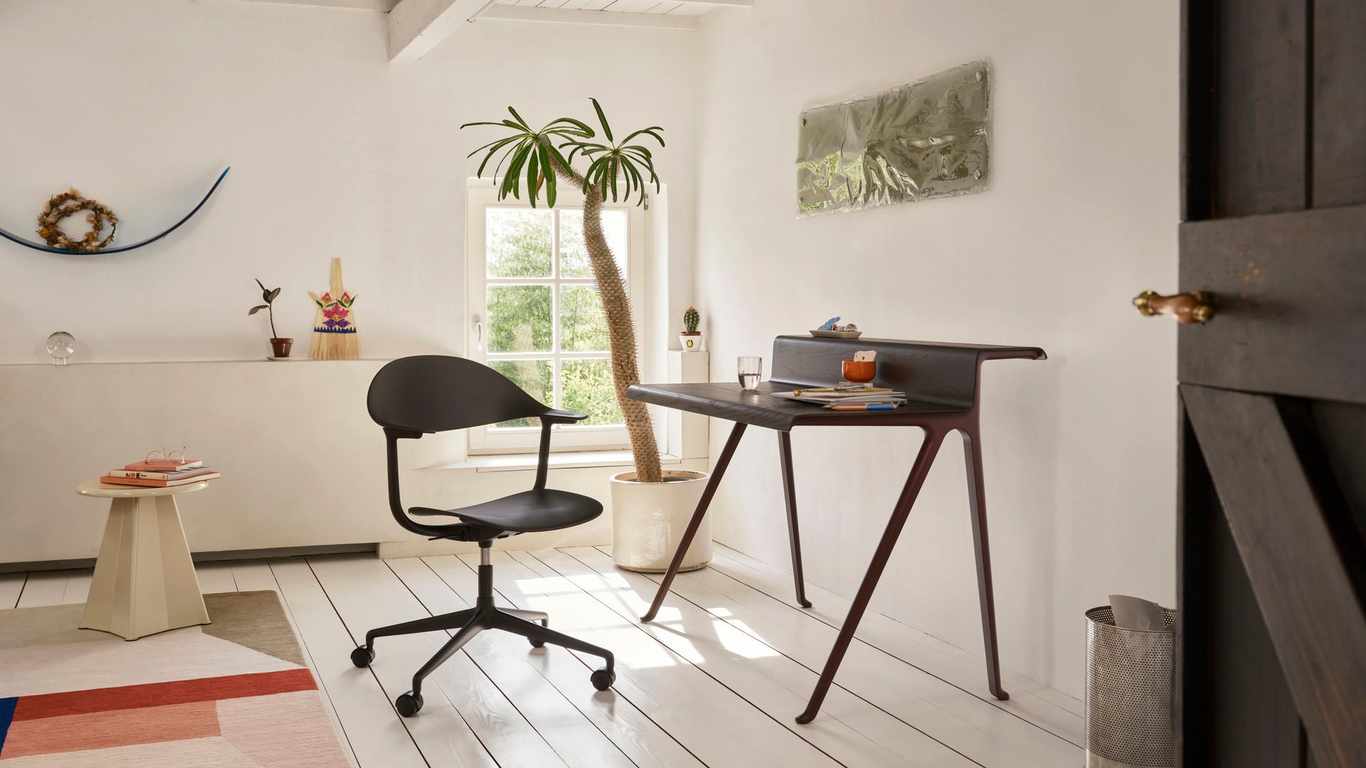 Modern office setup with a desk, chair, and decorative elements in a bright room.