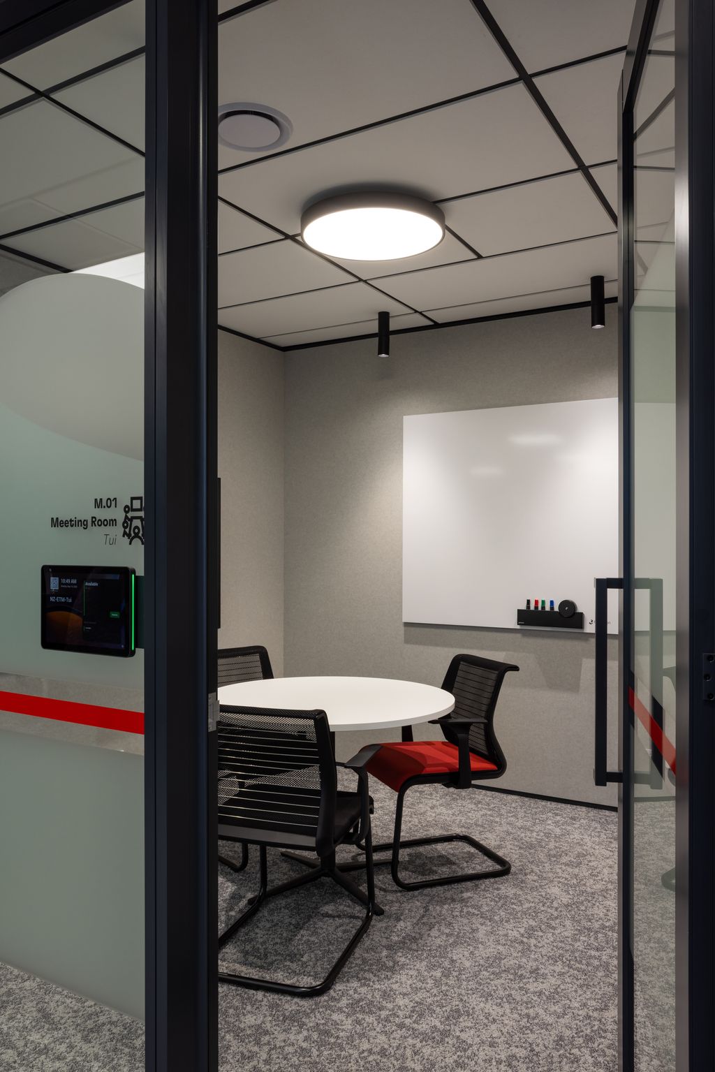 Conference room with round table and chairs, whiteboard on the wall.